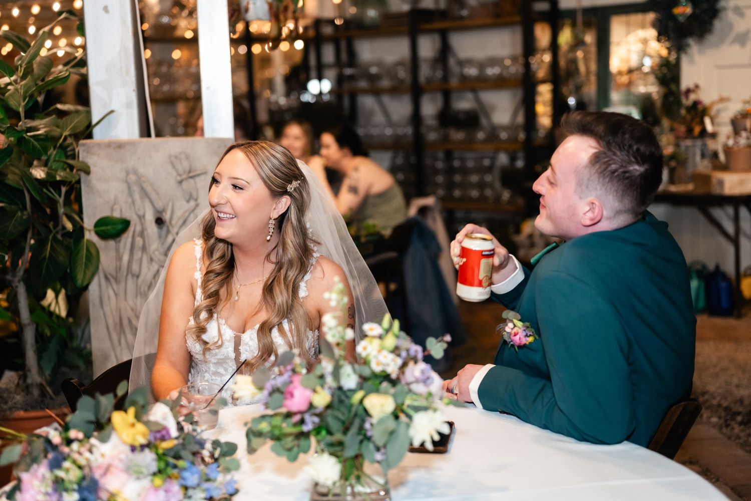 A couple shares a candid laughing moment at an elegant dining table decorated with floral centerpieces.