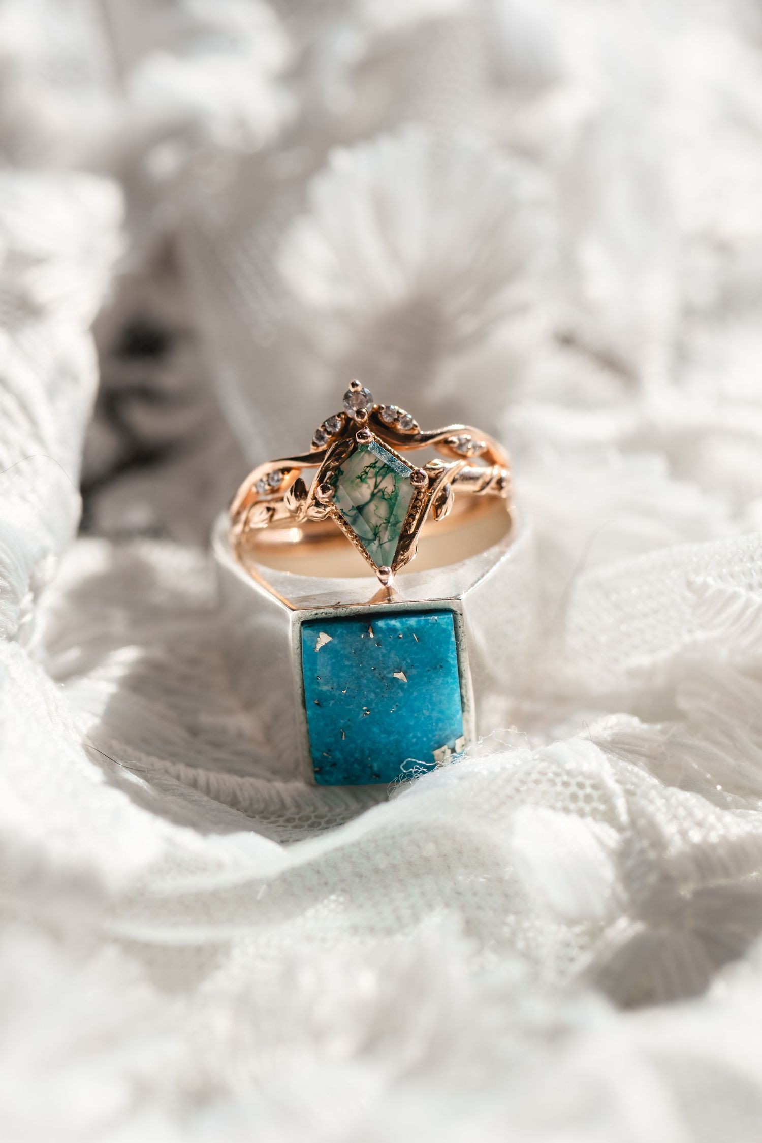 Rose gold engagement ring with turquoise stone displayed on a blue velvet ring box with lace background.