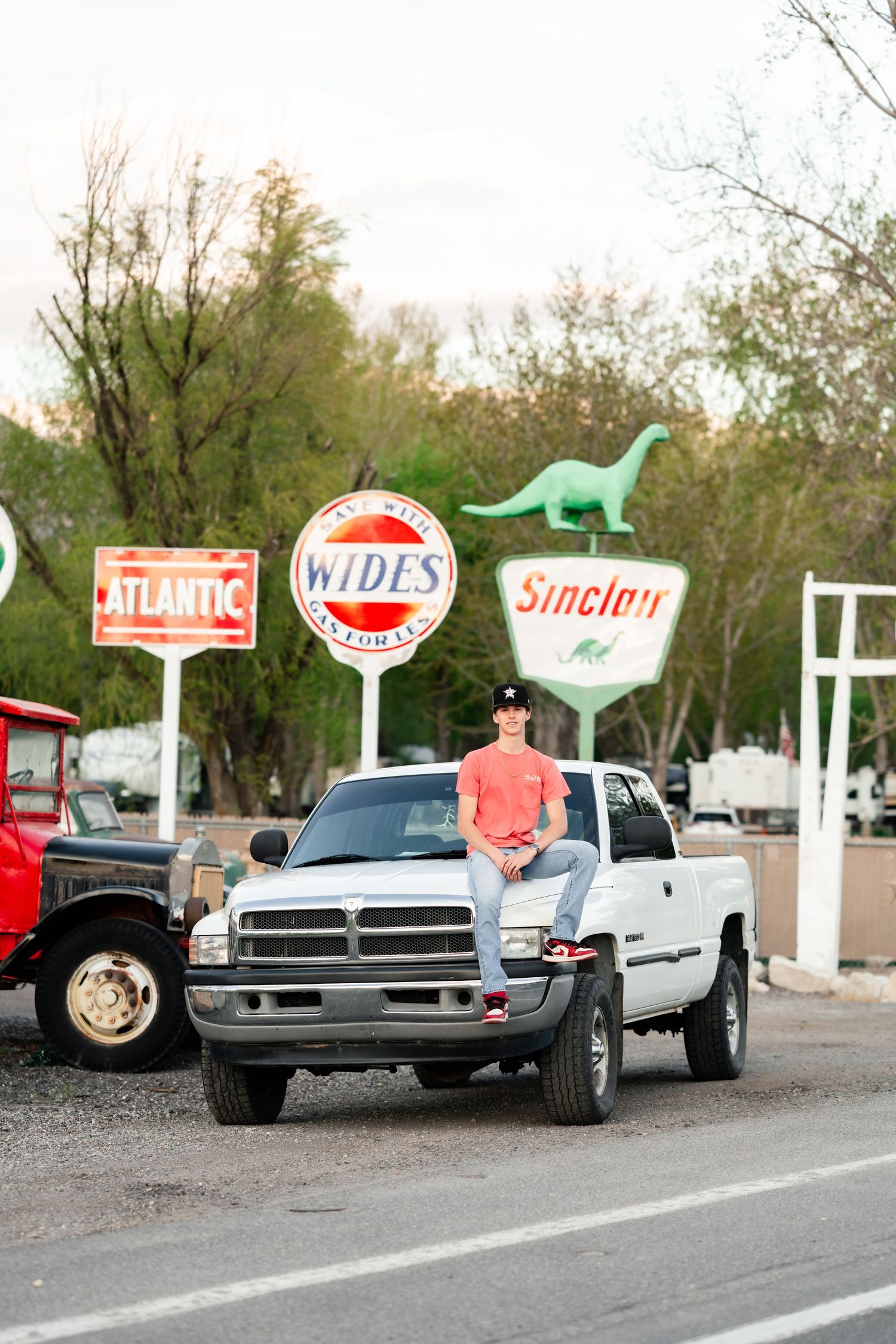 Vintage gas station signs and classic pickup trucks lined up in a row at an outdoor display.
