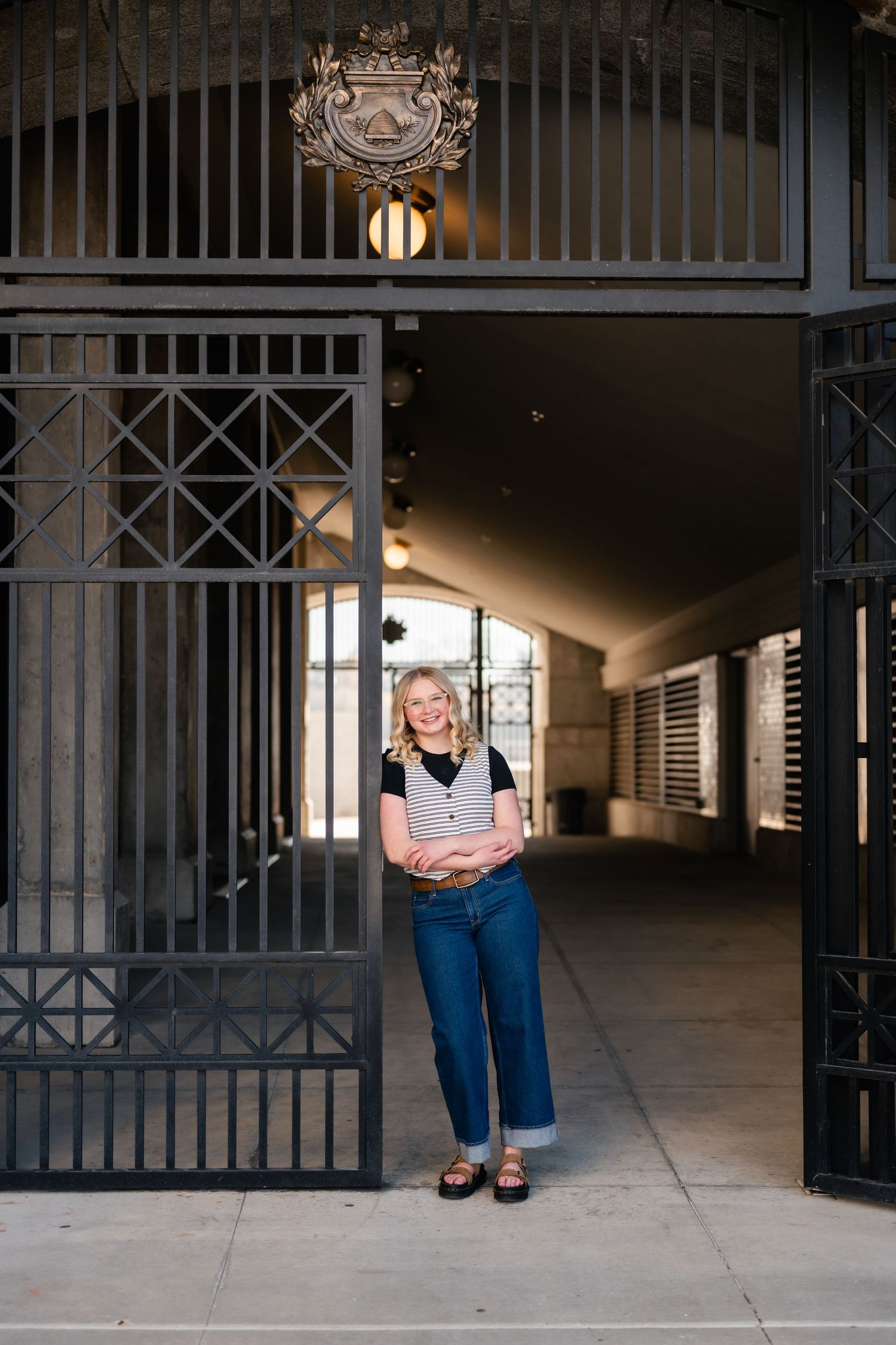 A series of artistic portraits showing someone sitting in front of an ornate metal gate in different poses.