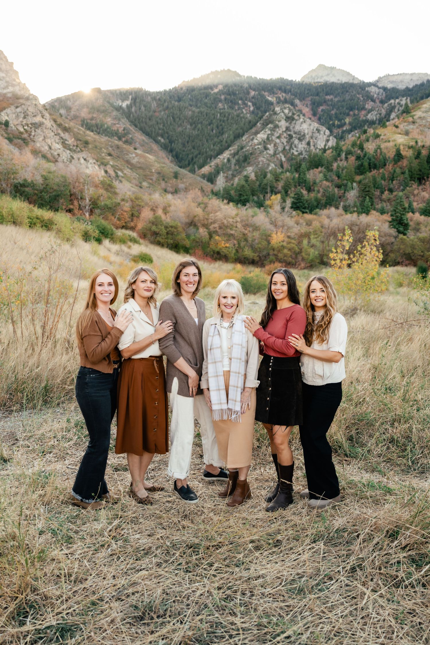 A group poses together for a family portrait in front of scenic mountain landscape.