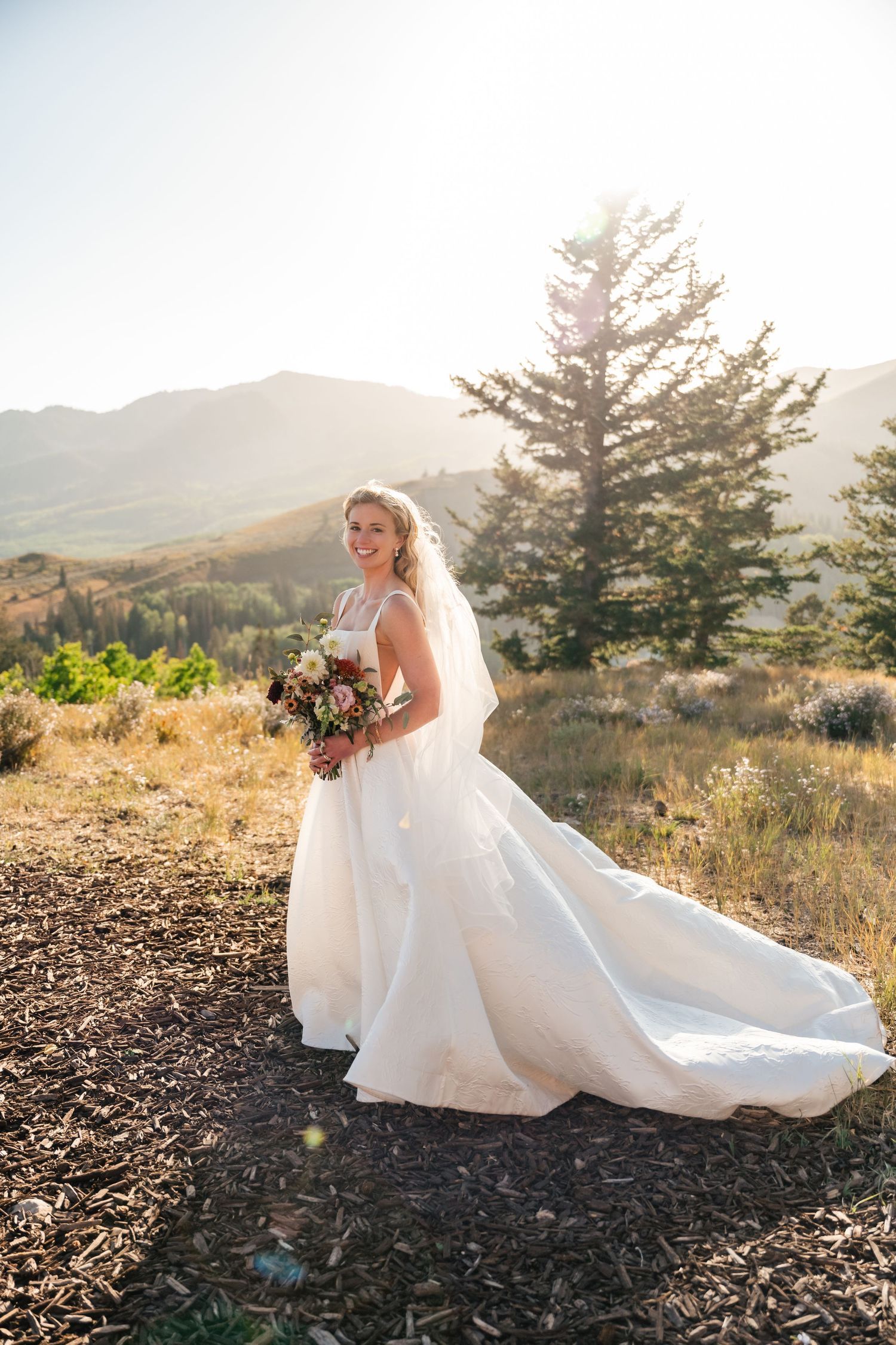 Scenic bridal portraits at sunset with mountain views and flowing white dress.