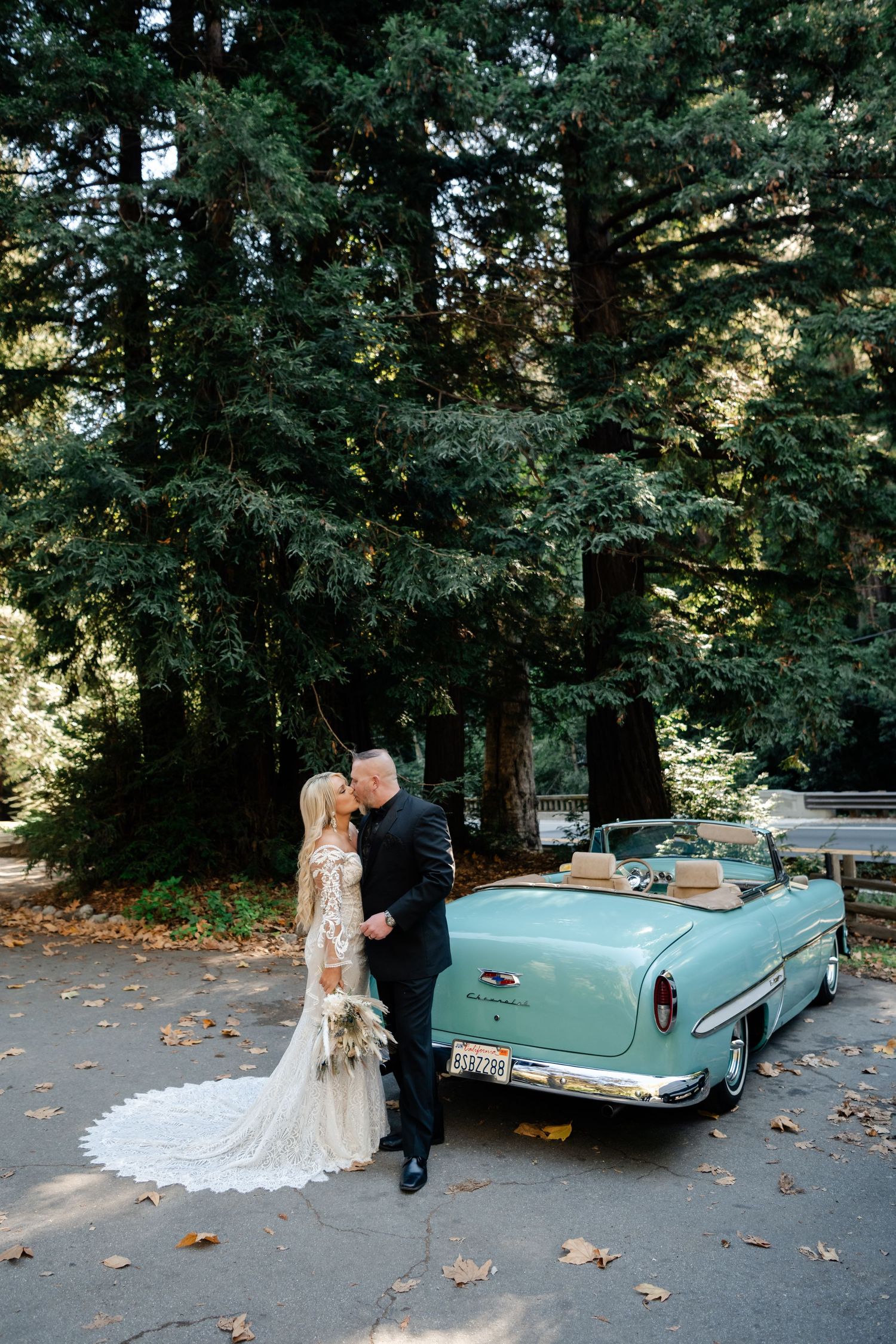 Elegant wedding photo shoot with vintage mint convertible in wooded park setting.