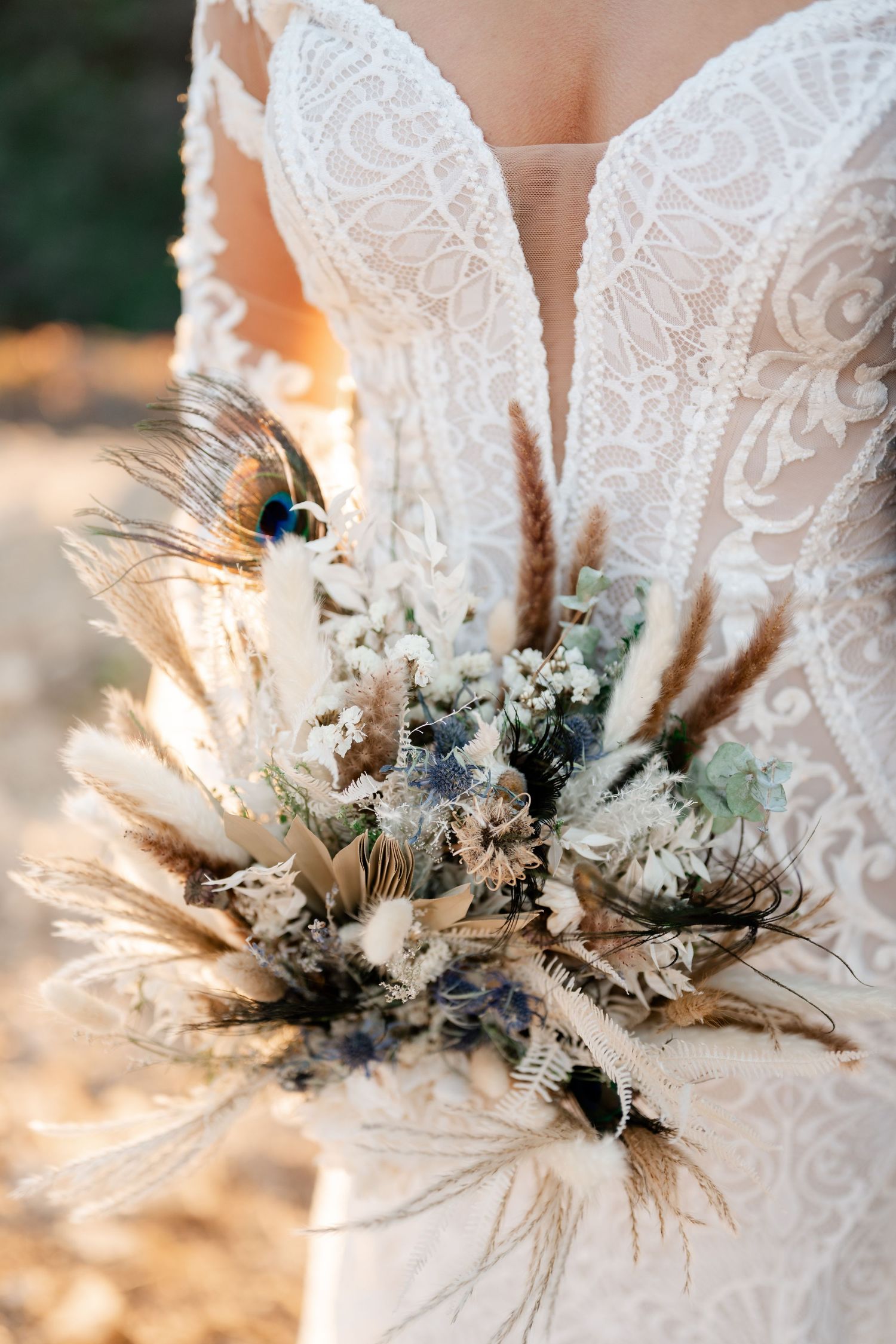 Detailed view of a white lace wedding dress bodice adorned with a dried flower bouquet arrangement.