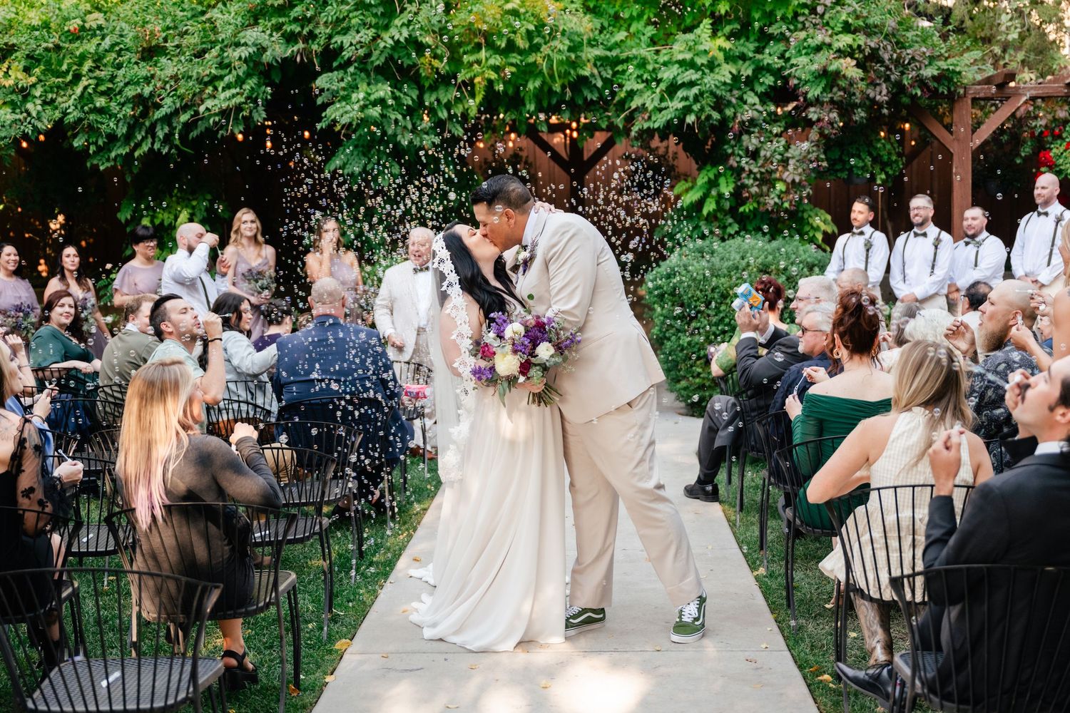 Wedding guests celebrate outdoors in a lush garden setting at Alpine Art Center, a Utah County Wedding Venue.