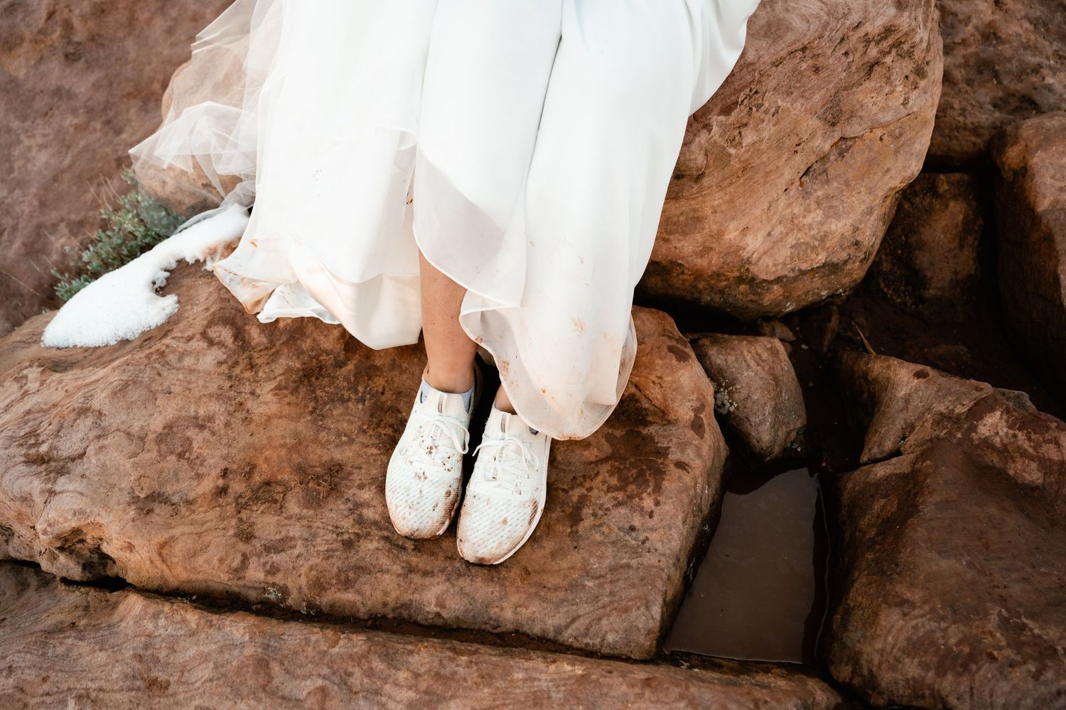 Close-up of white wedding dress details against red rock background.