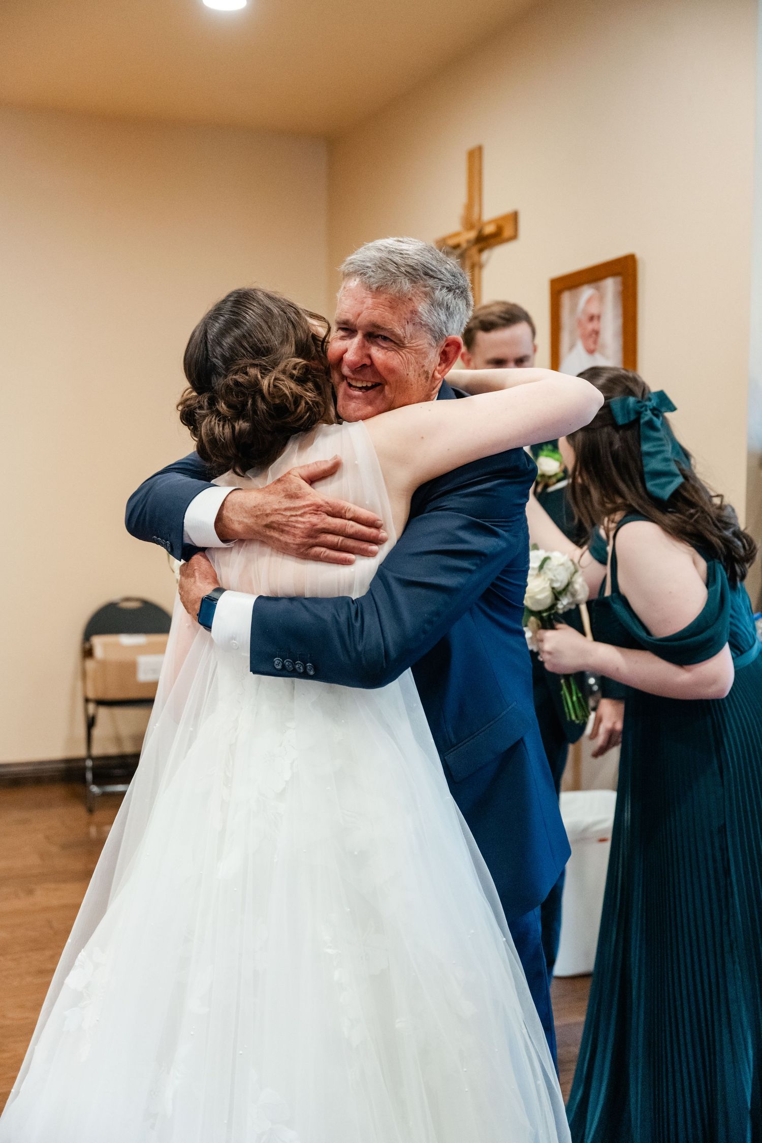 Emotional sequence of wedding reception hugs between guests and family members in a church hall setting.