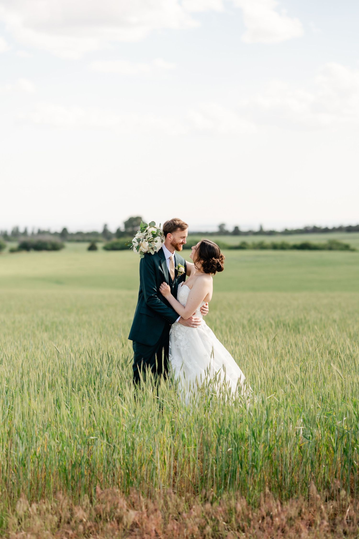 A couple shares an intimate moment in a serene wheat field on their wedding day.