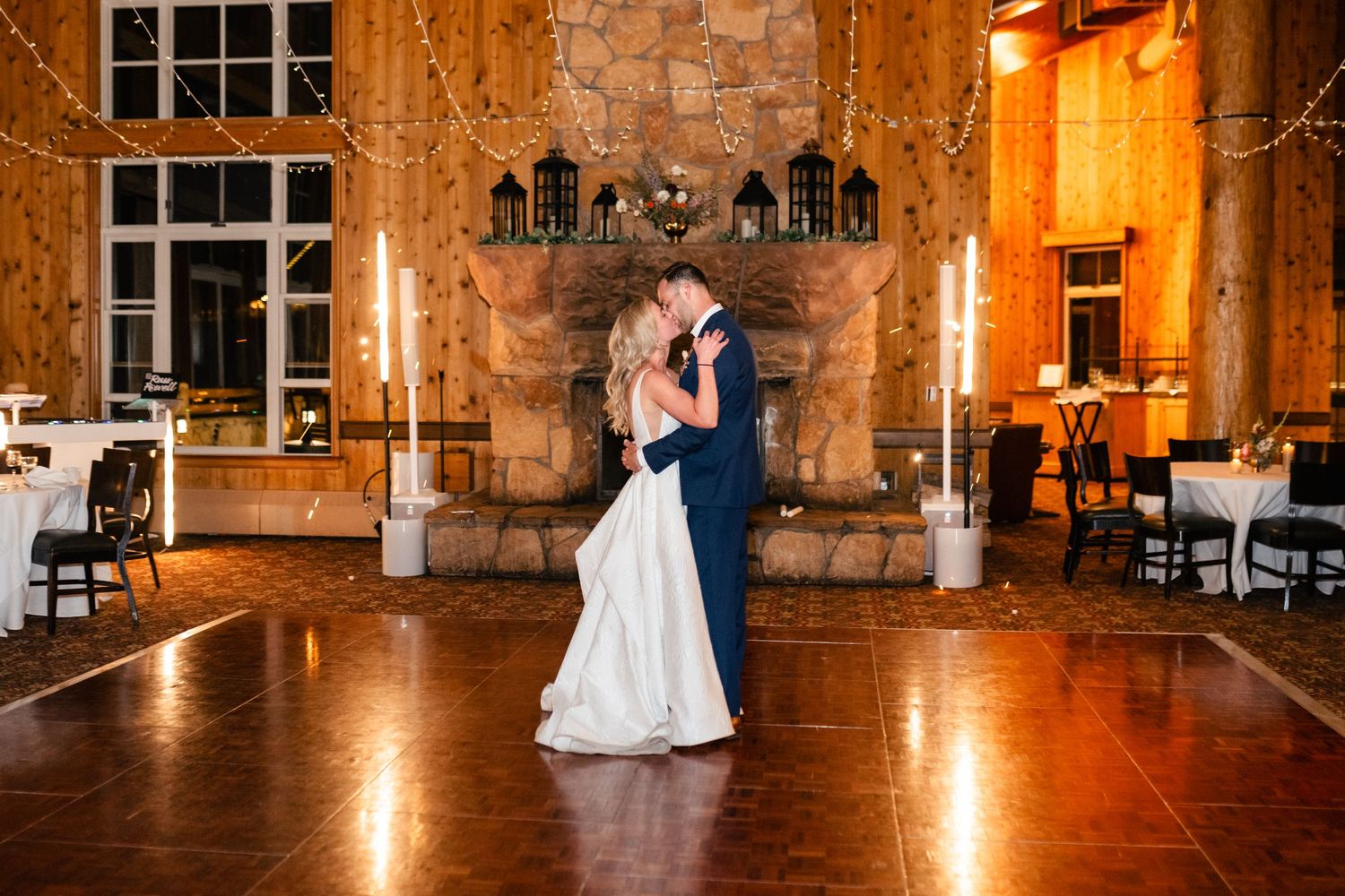 Rustic wedding venue interior with stone walls illuminated by warm lighting and string lights.
