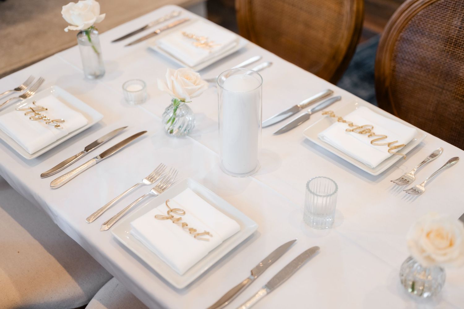 Elegant place settings with name cards arranged on white tablecloths at a formal reception.