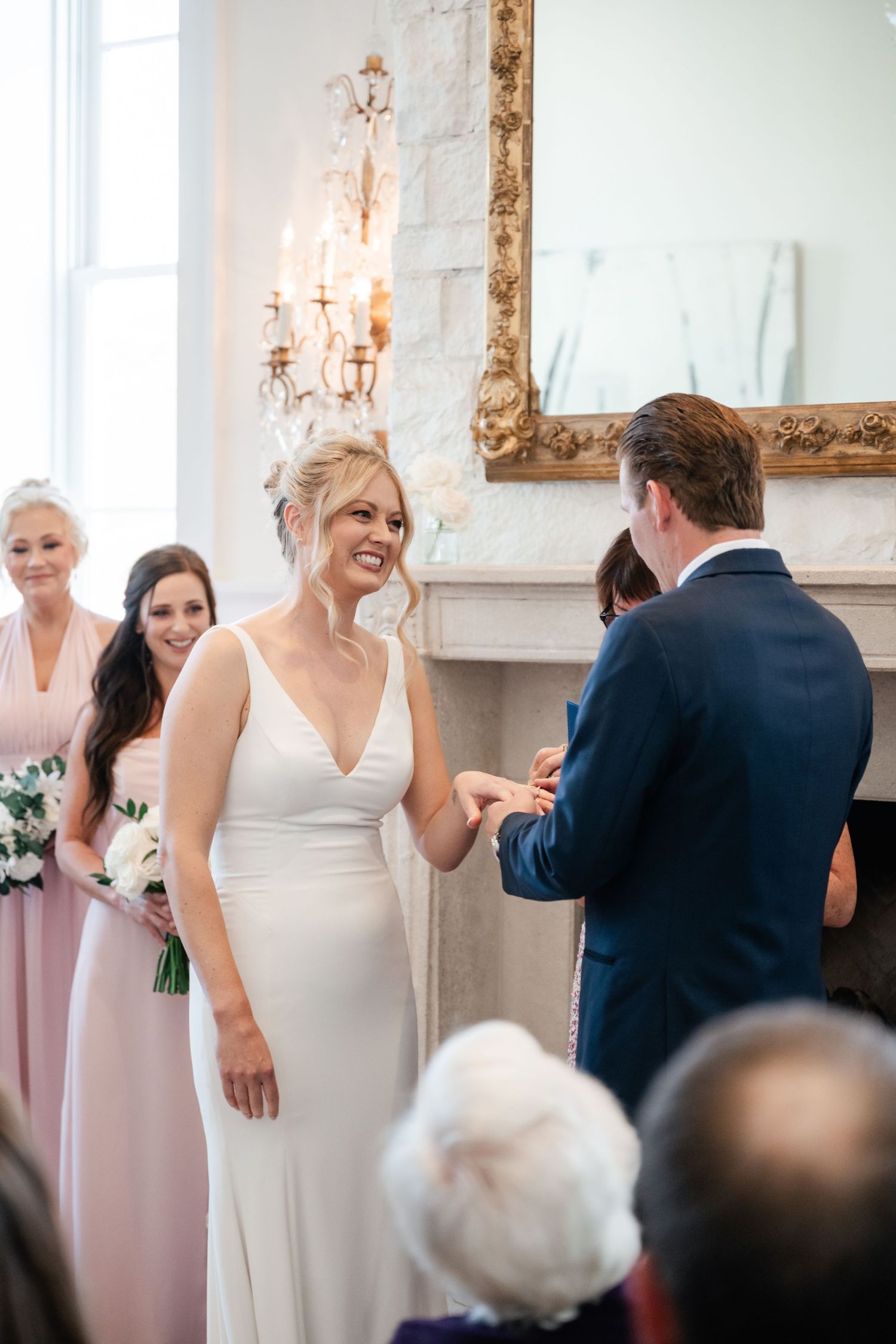 Wedding celebration candid moments captured in an elegant white room with gold-framed mirrors.
