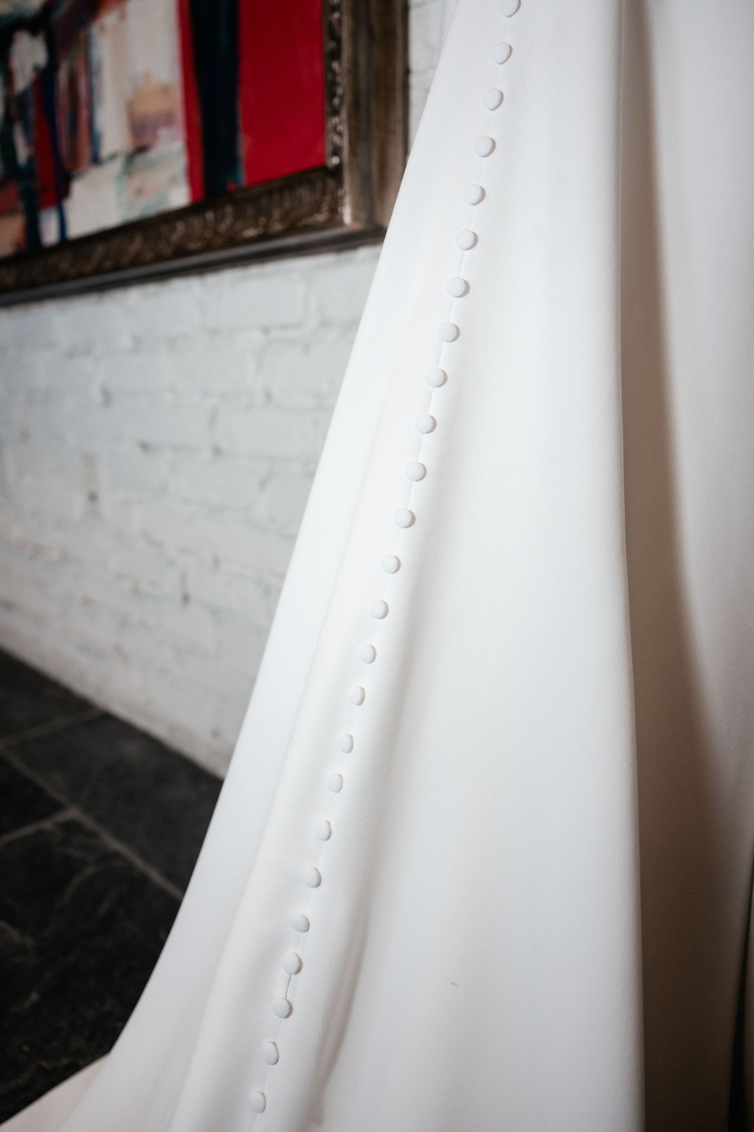Close-up detail of white wedding dress buttons in a row against a light background.