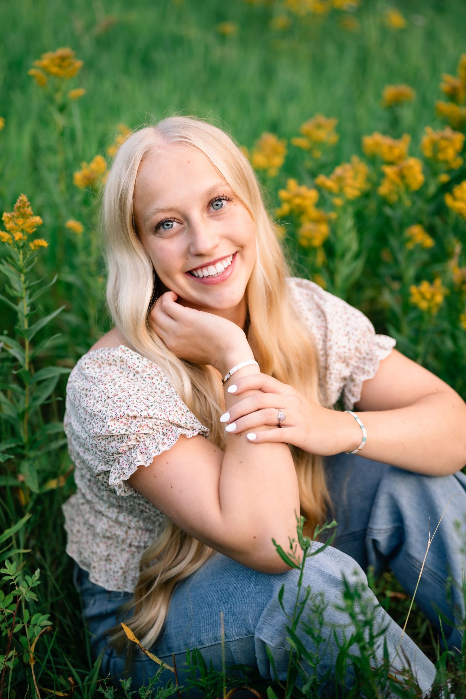 Sitting and smiling portrait in a field of wildflowers by Utah Senior Photographer, Coley Cook