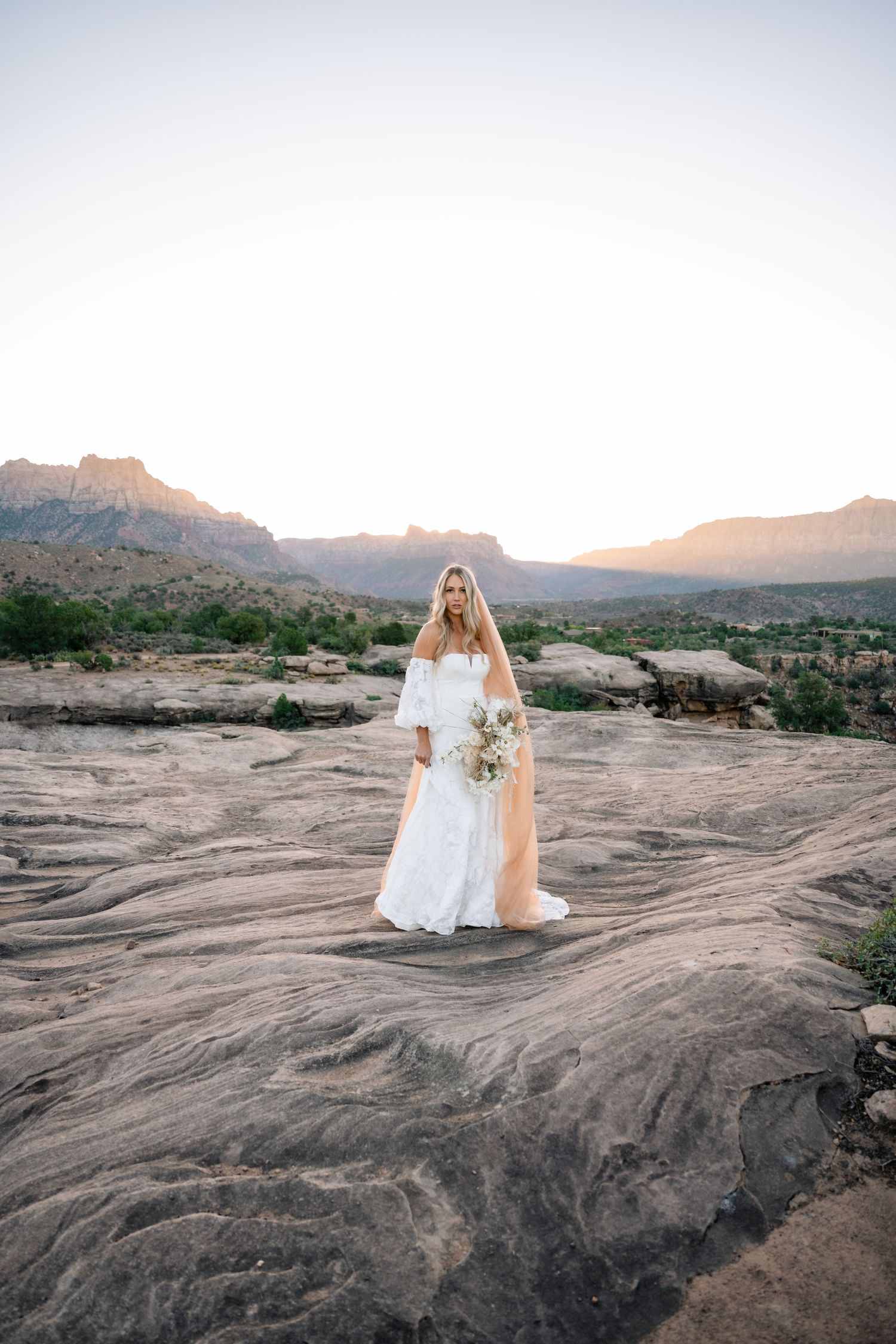 Zions wedding photographer takes beautiful desert sunrise bridals featuring a unique veil and dried floral bouquet.