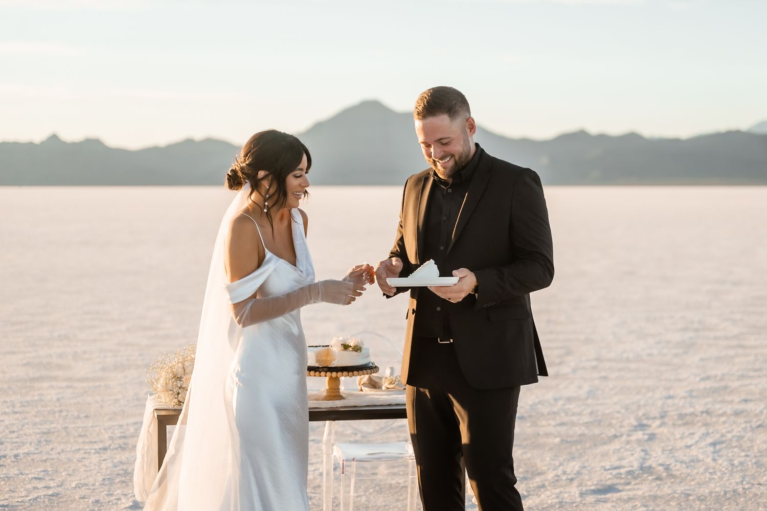 A couple shares a joyful moment during their wedding ceremony on a vast salt flat.