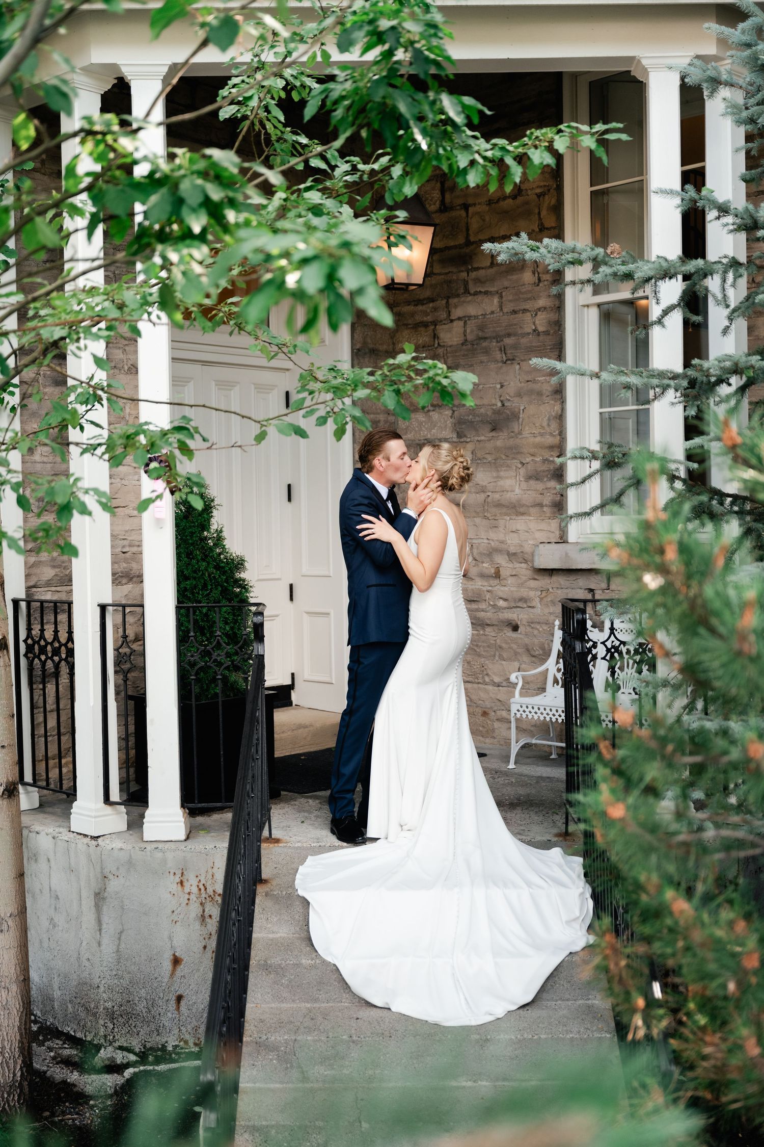 A tender moment between newlyweds on a charming stone porch with white columns.