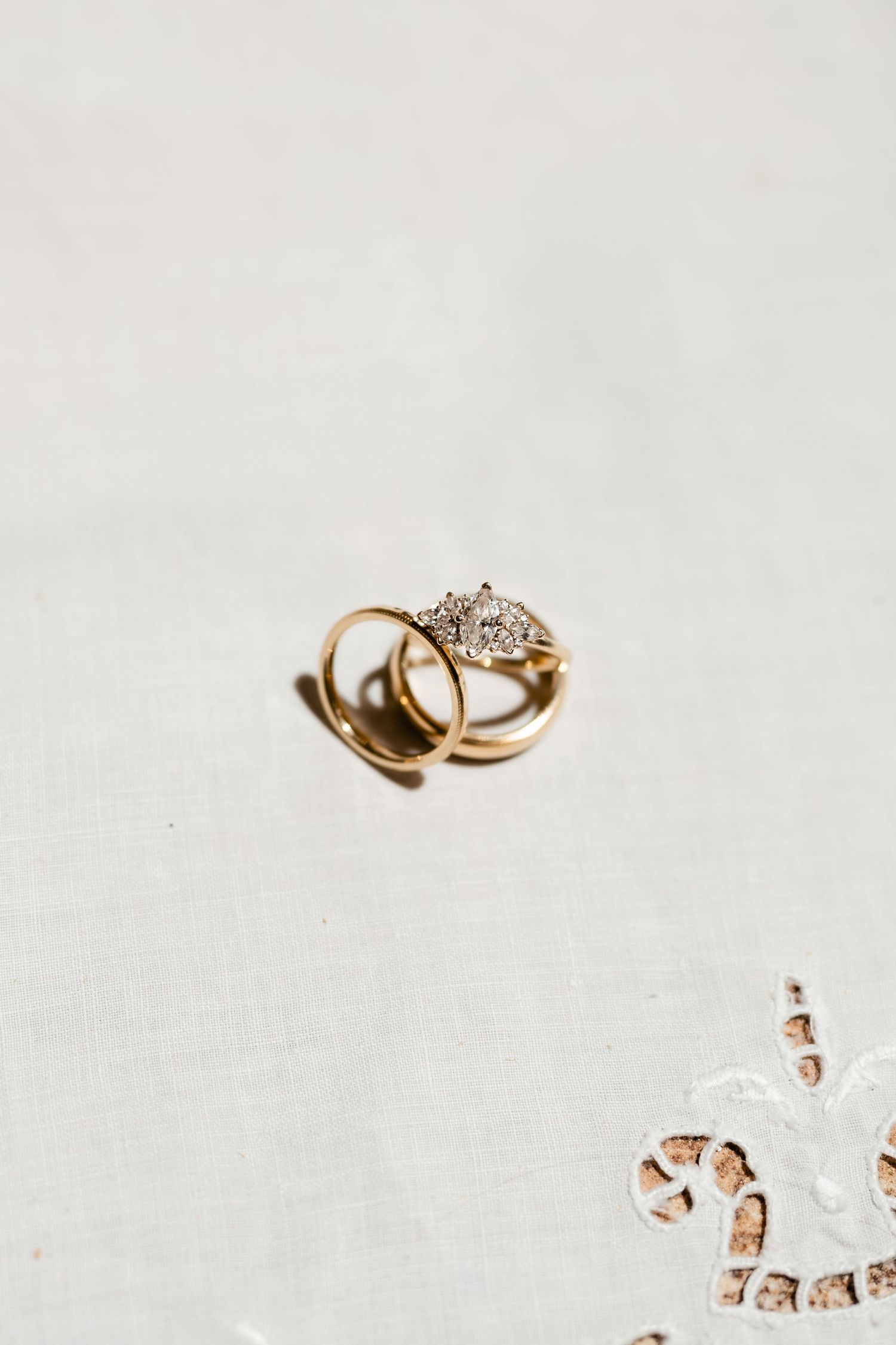 Wedding rings photographed in artistic arrangement on white background with crystal details.