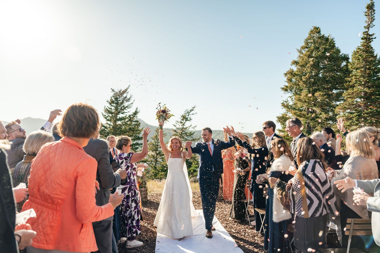 Wedding guests celebrating and cheering during an outdoor mountain ceremony.