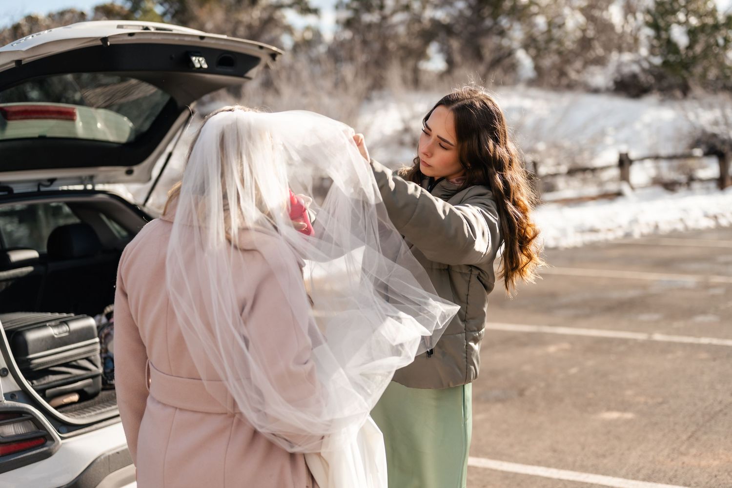 White dress flowing in the wind against snowy red rock landscape.
