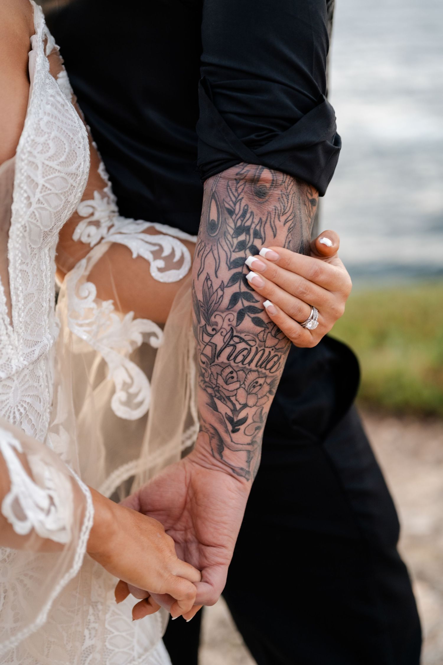 Close-up of detailed floral tattoo artwork and lace wedding dress details.