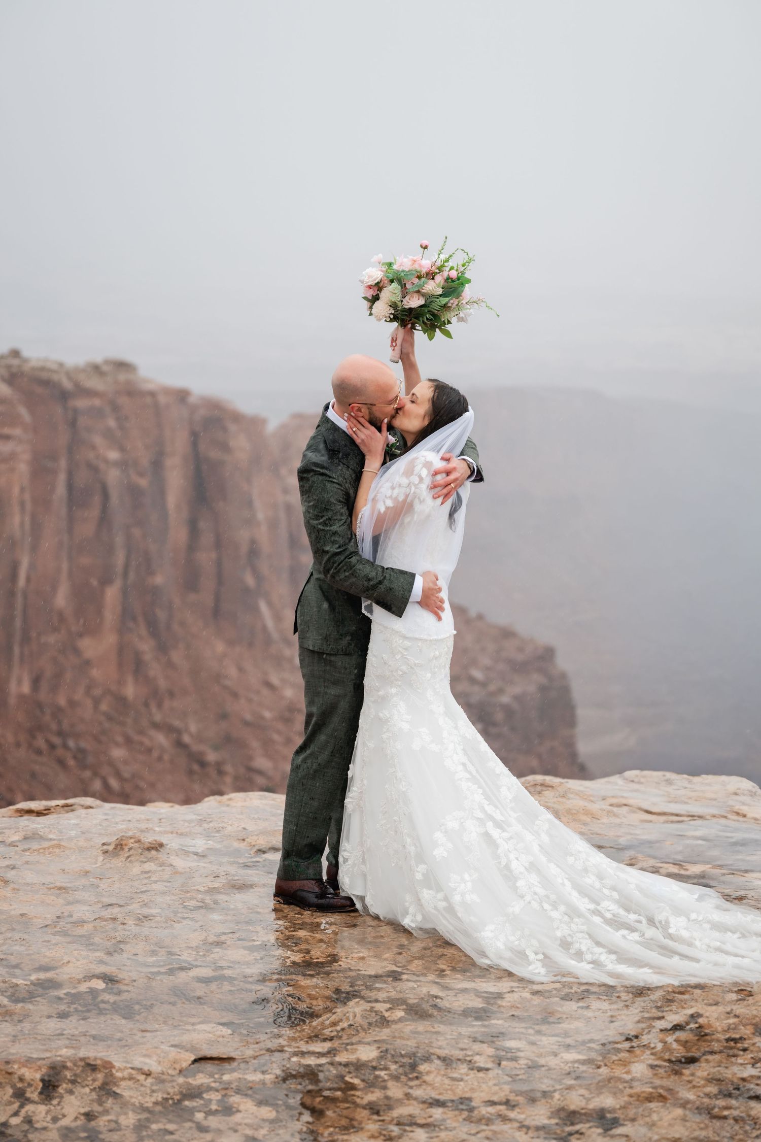 Romantic wedding photos captured on a dramatic cliff edge with red rock formations in the background.