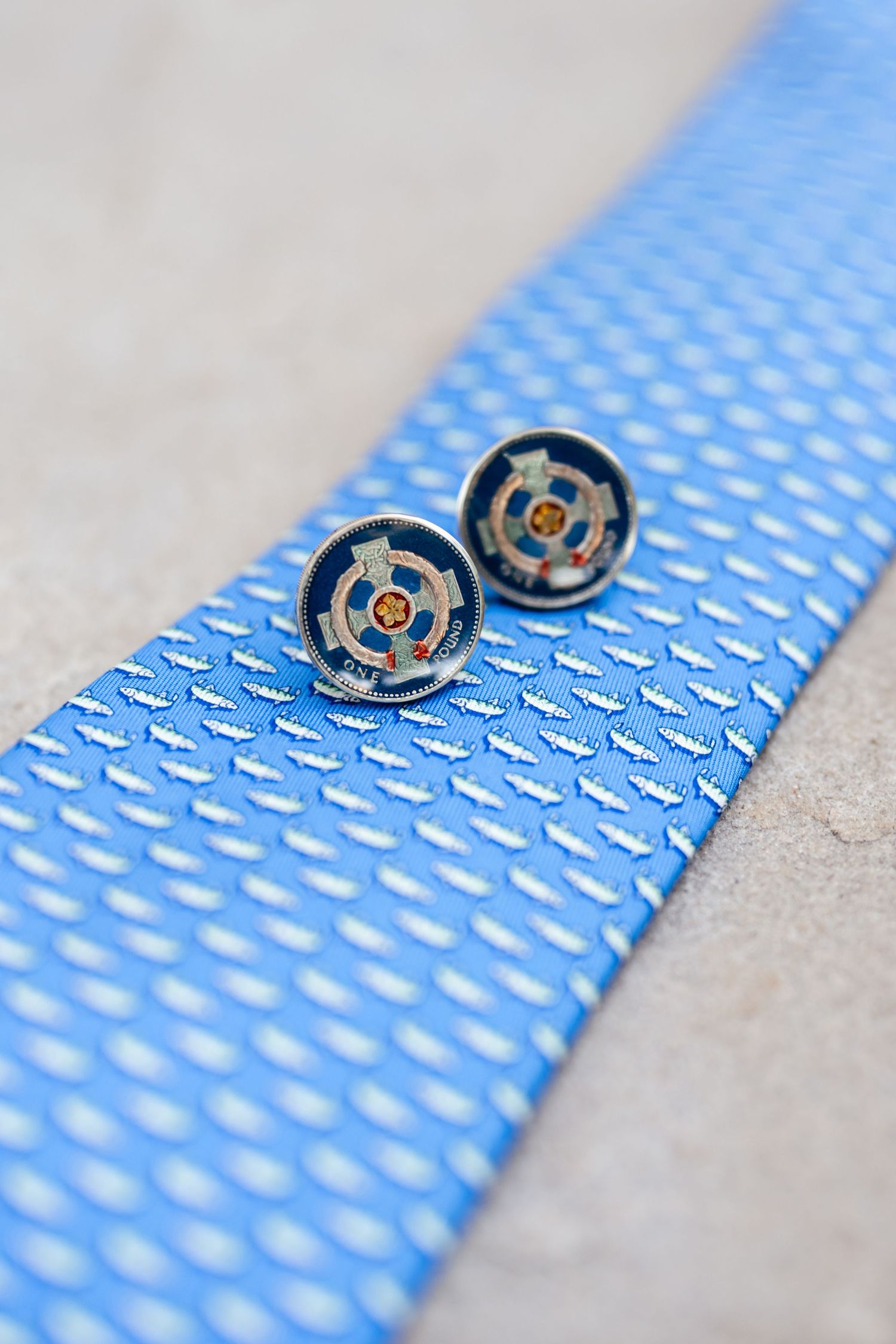 Close-up detail of a light blue textured necktie with black buttons.