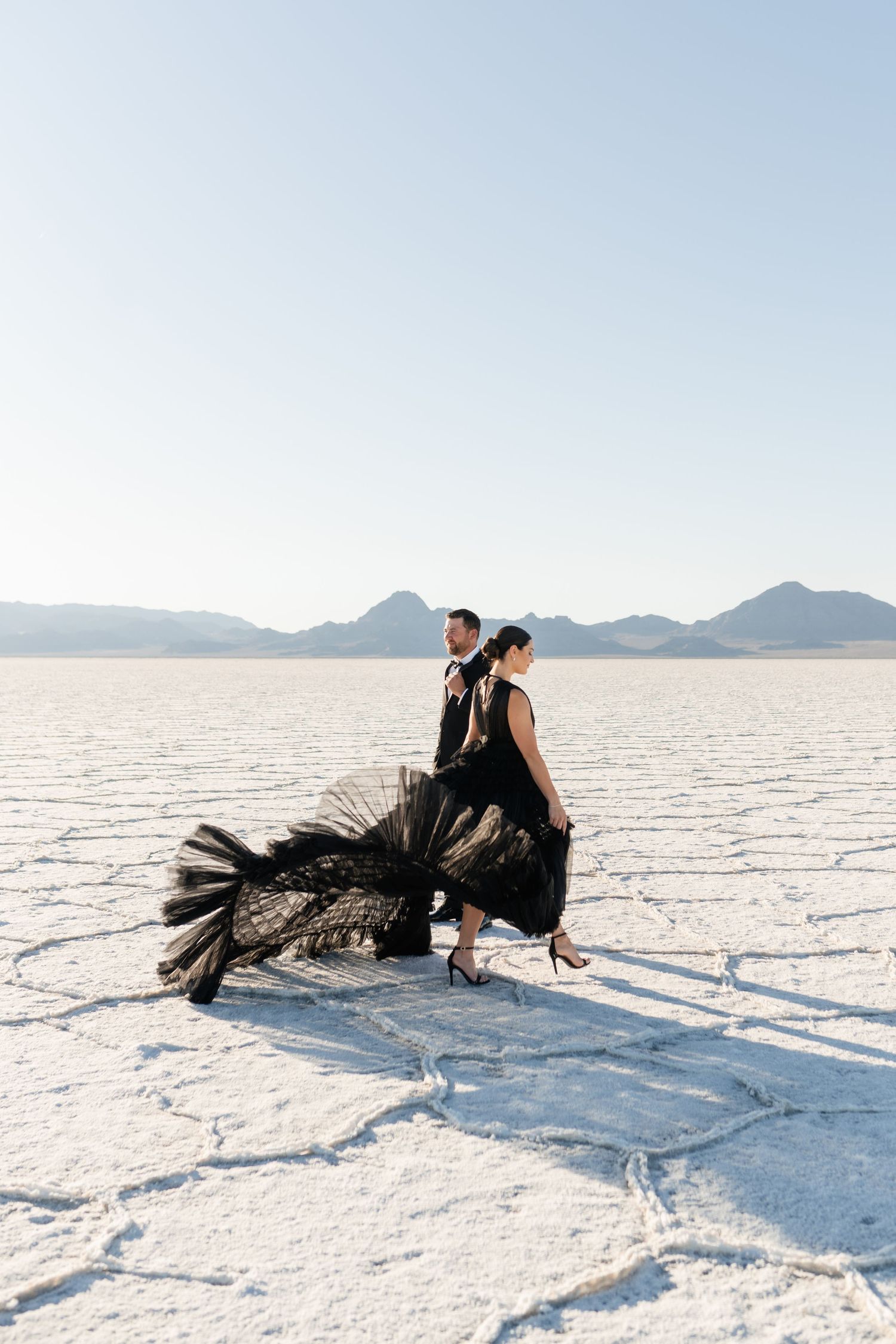 Salt Flats Photographer. A dramatic black gown with tulle details photographed against a stark white salt flat landscape at sunset.