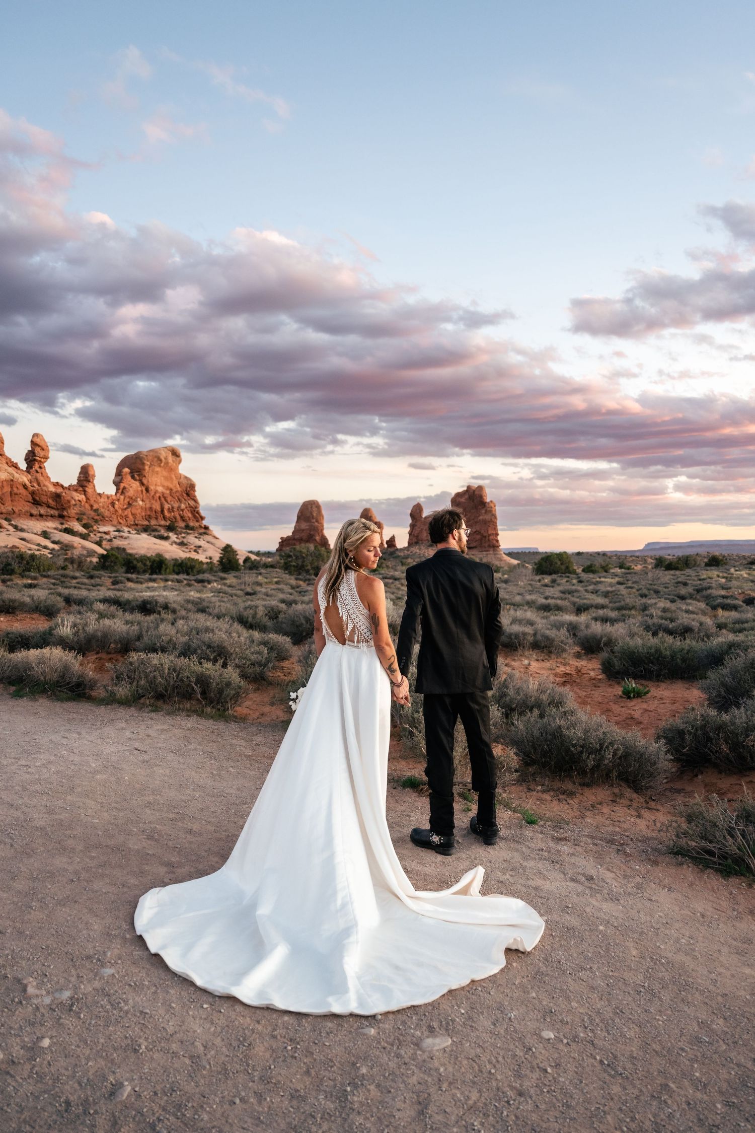 Elopement couple hold hands in Arches National Park by Utah Elopement Photographer and videographer