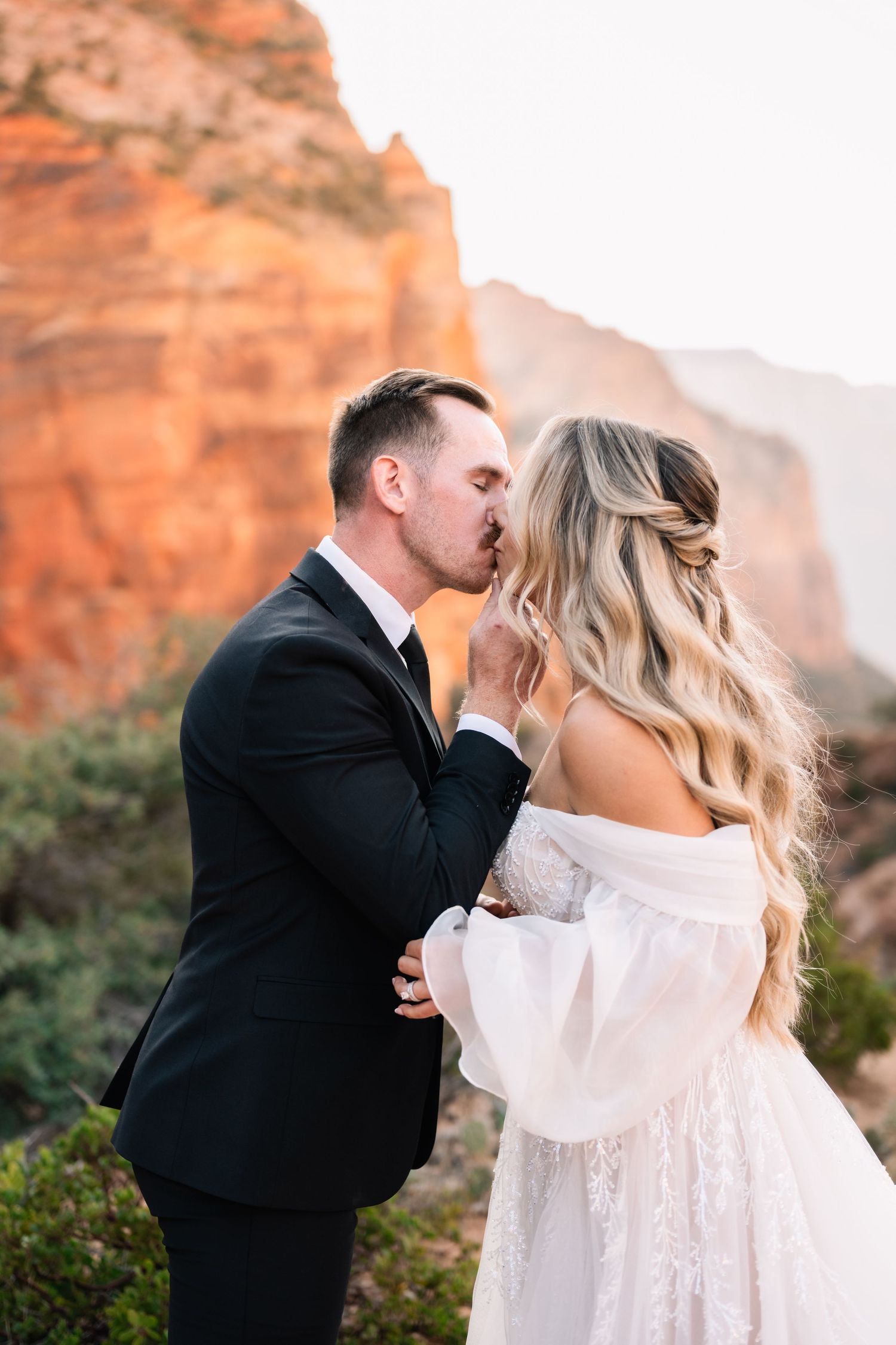 Intimate wedding moment captured against stunning red rock canyon backdrop.