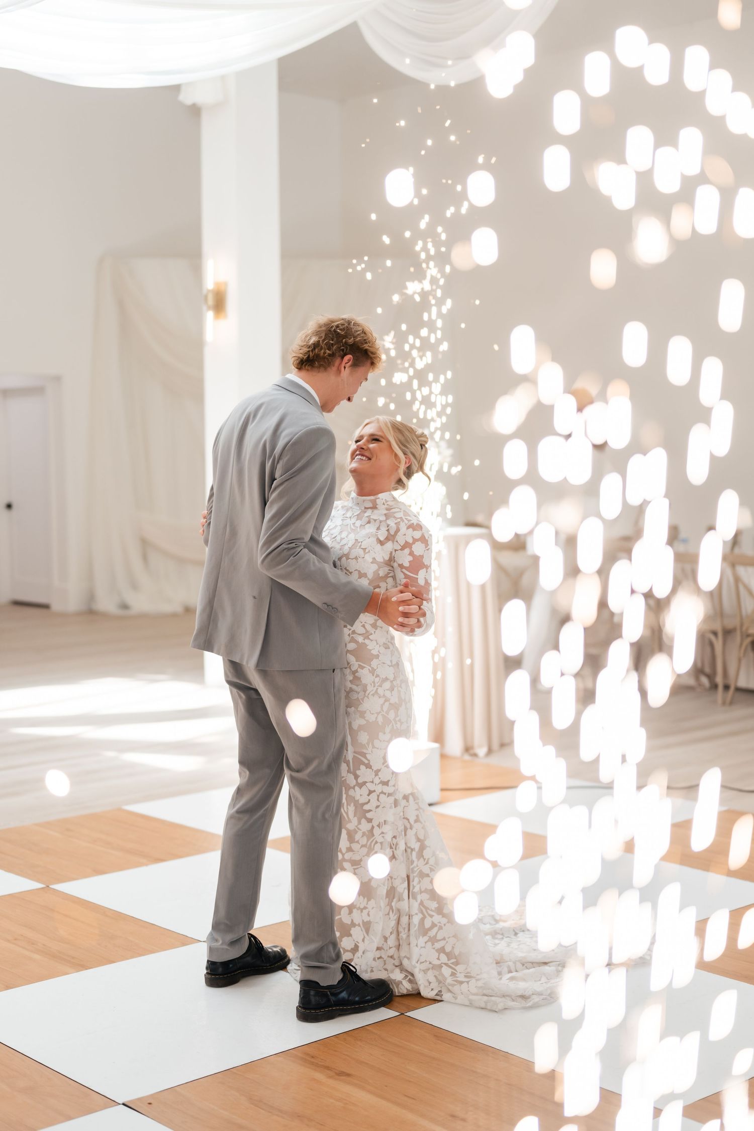 A couple in elegant wedding attire dancing together at Moments on Main with beautiful cool sparklers during their first dance.