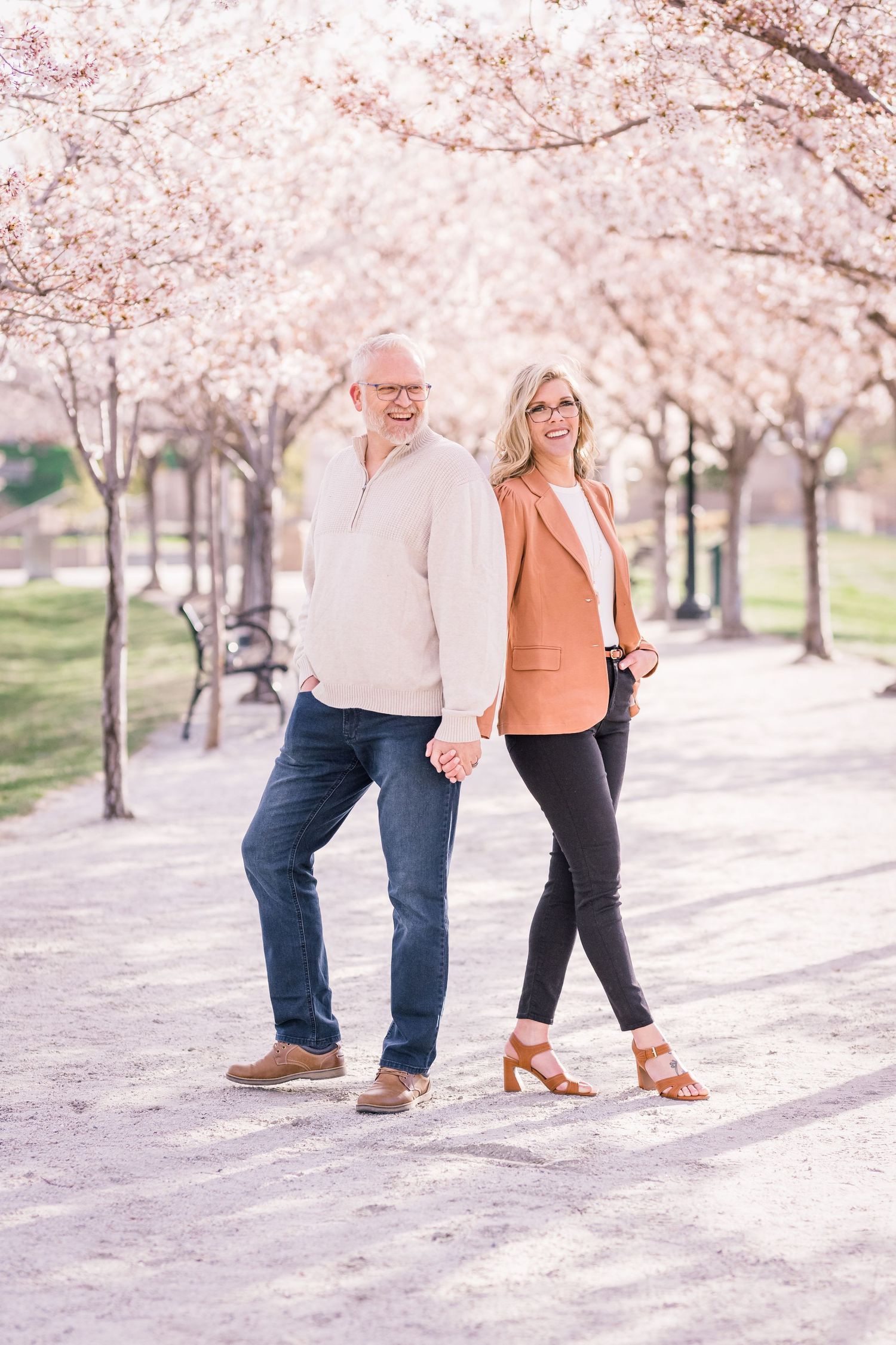 Couple stands back to back holding hands at the Capitol blossoms by Utah engagement photographer