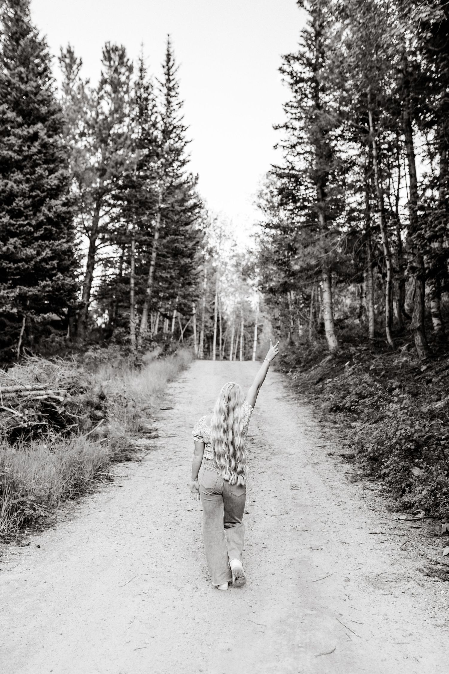 Black and white playful walking portrait down a dirt road in the mountains