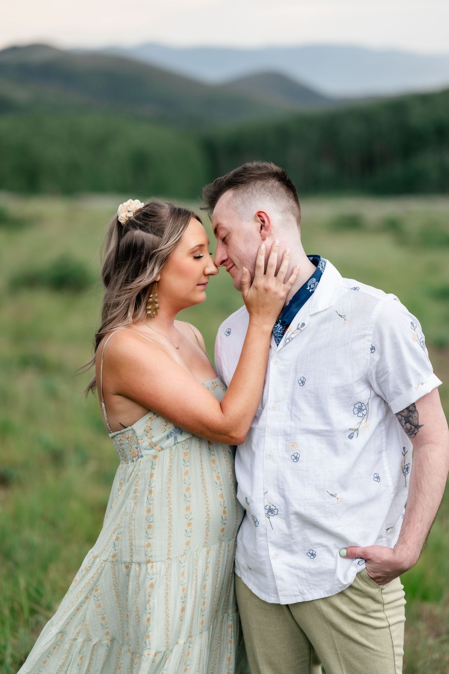 Intimate moment between couple in casual attire against mountain backdrop during engagement photoshoot. Park City engagement photographer.