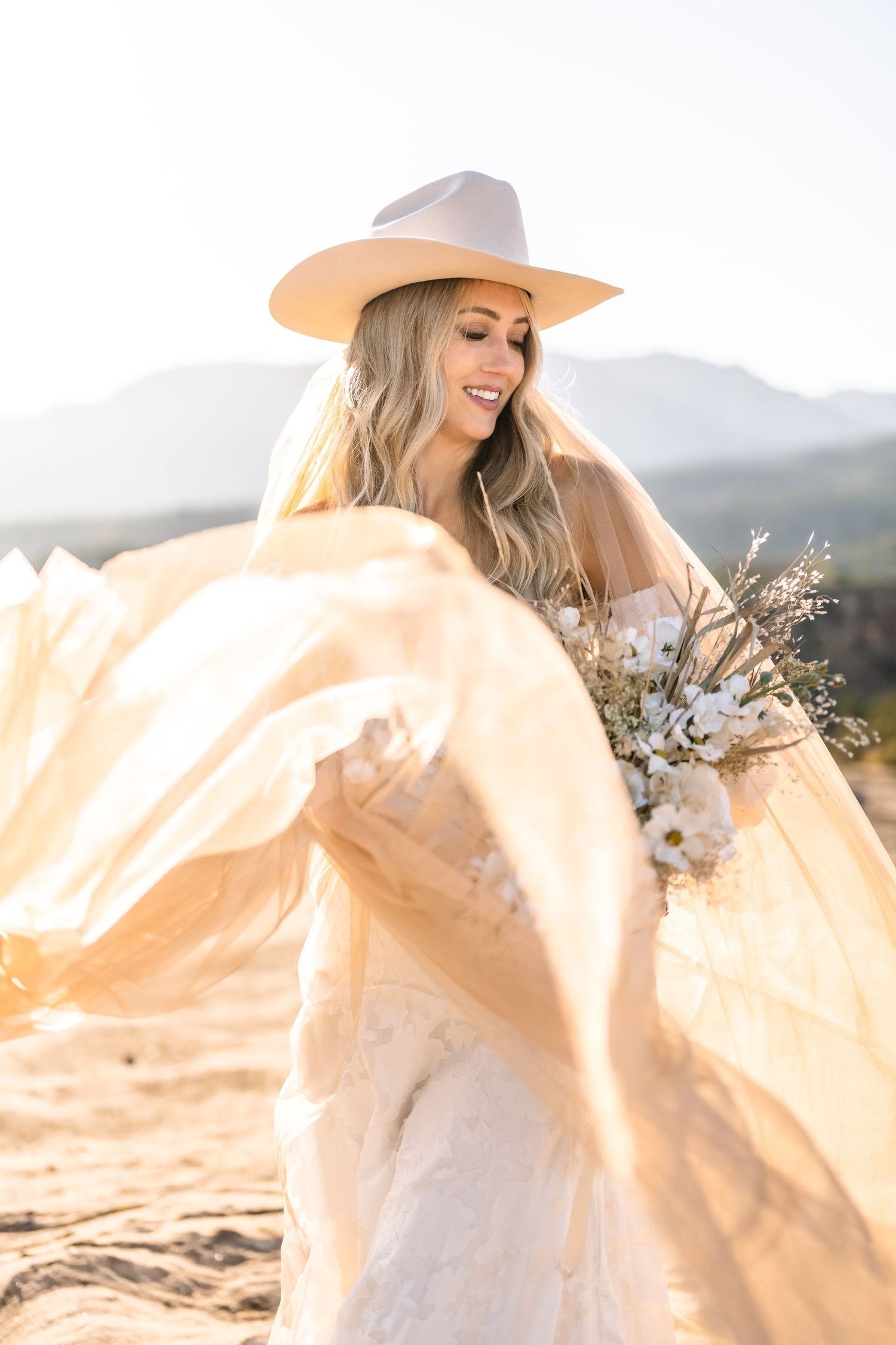 Utah elopement photographer takes breathtaking desert sunrise bridal session with a stunning bouquet and cowgirl hat.