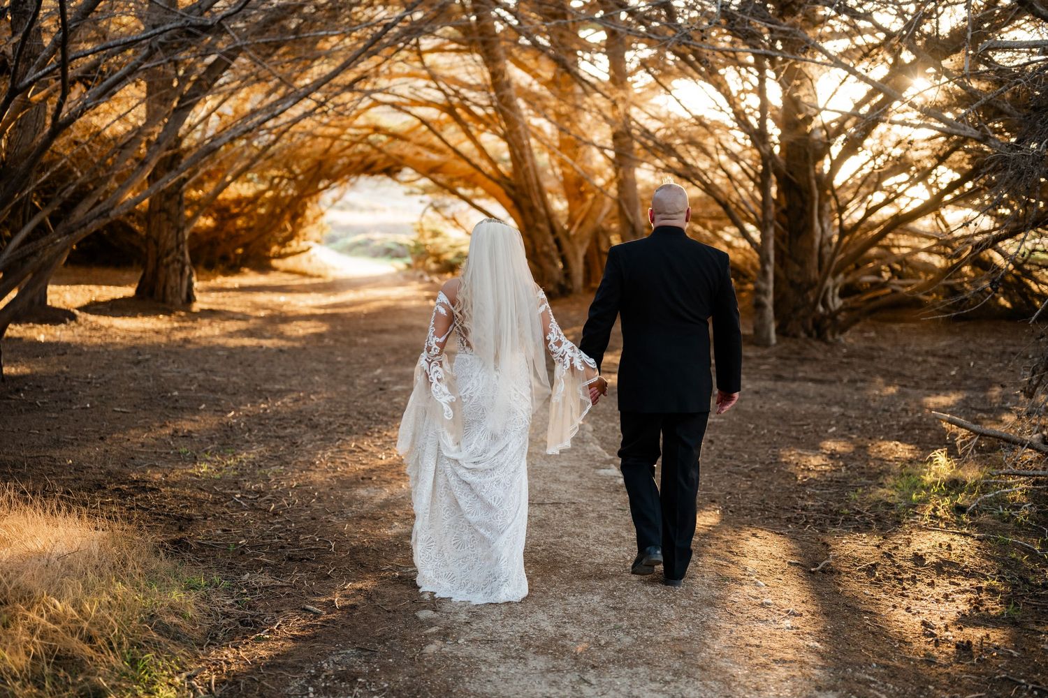 A couple walks along a sunlit path during golden hour.