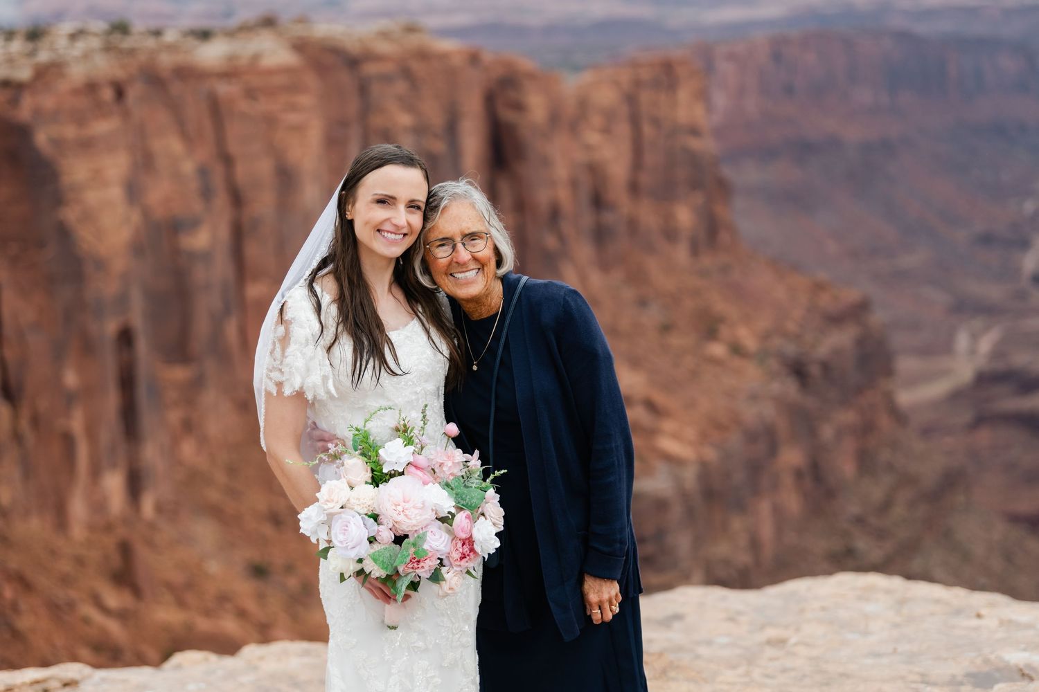 Couple shares intimate moment at scenic desert canyon overlook during their wedding celebration.