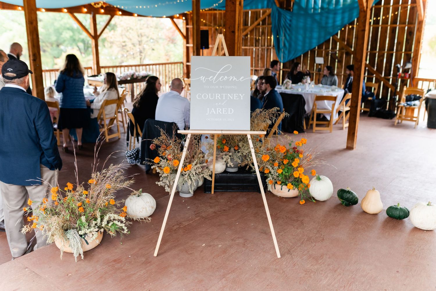 Wedding reception space decorated with blue draping and floral arrangements.