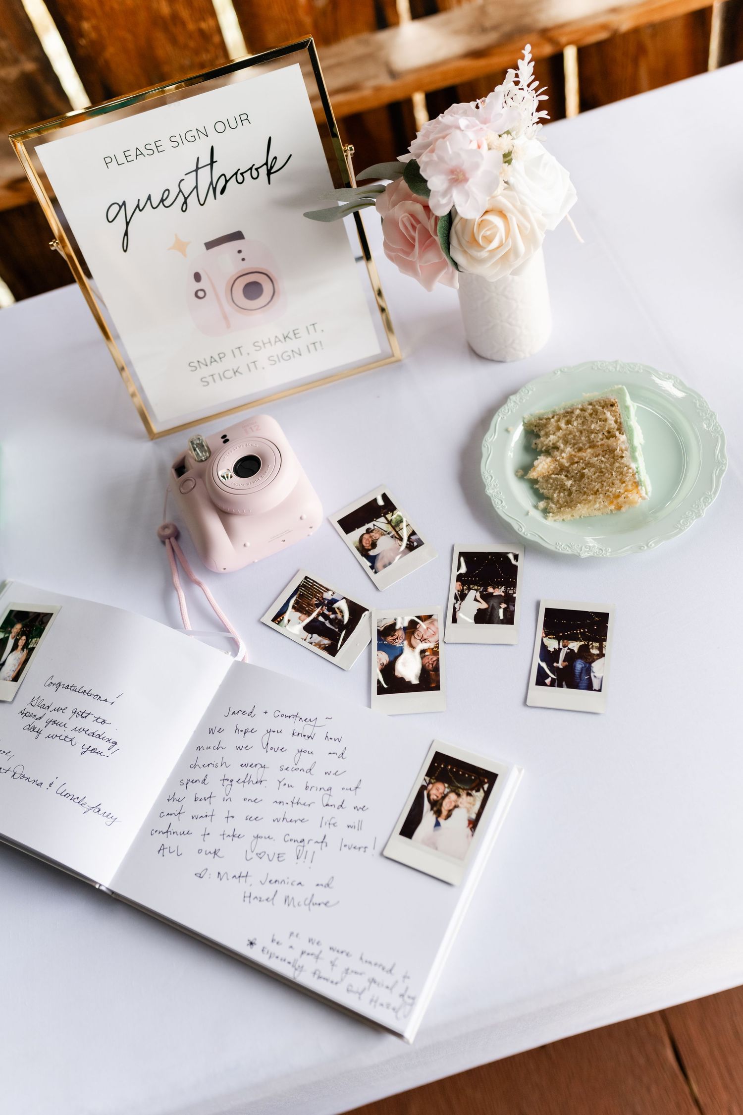 Wedding guestbook table setup with instant photos, pink decorations, and mint green plates.