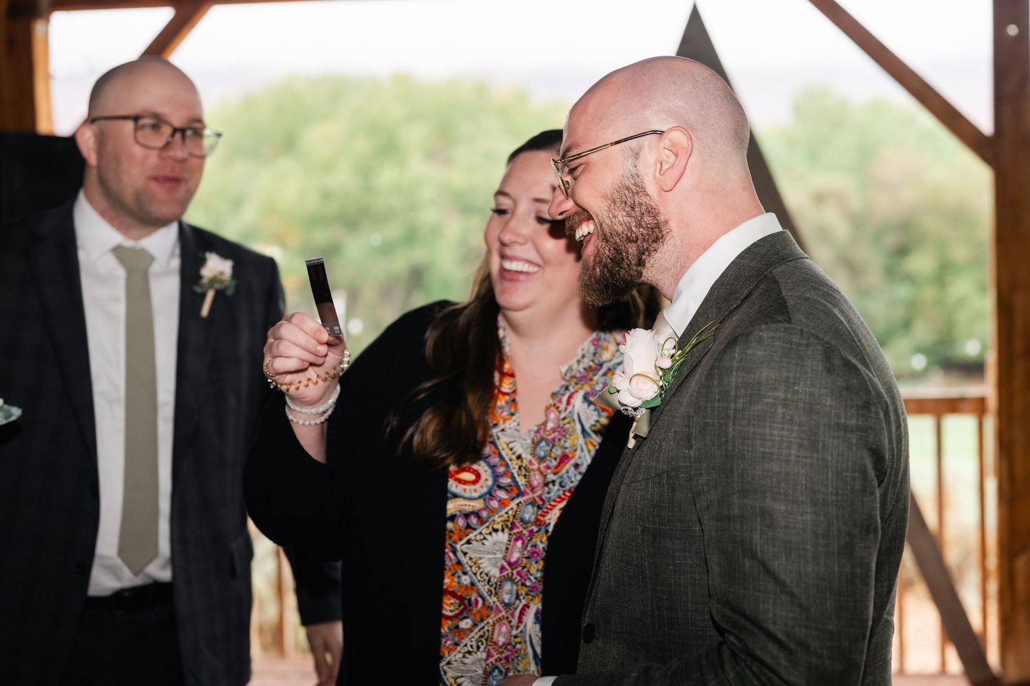 People engaged in conversation at an outdoor event with wooden beams overhead.