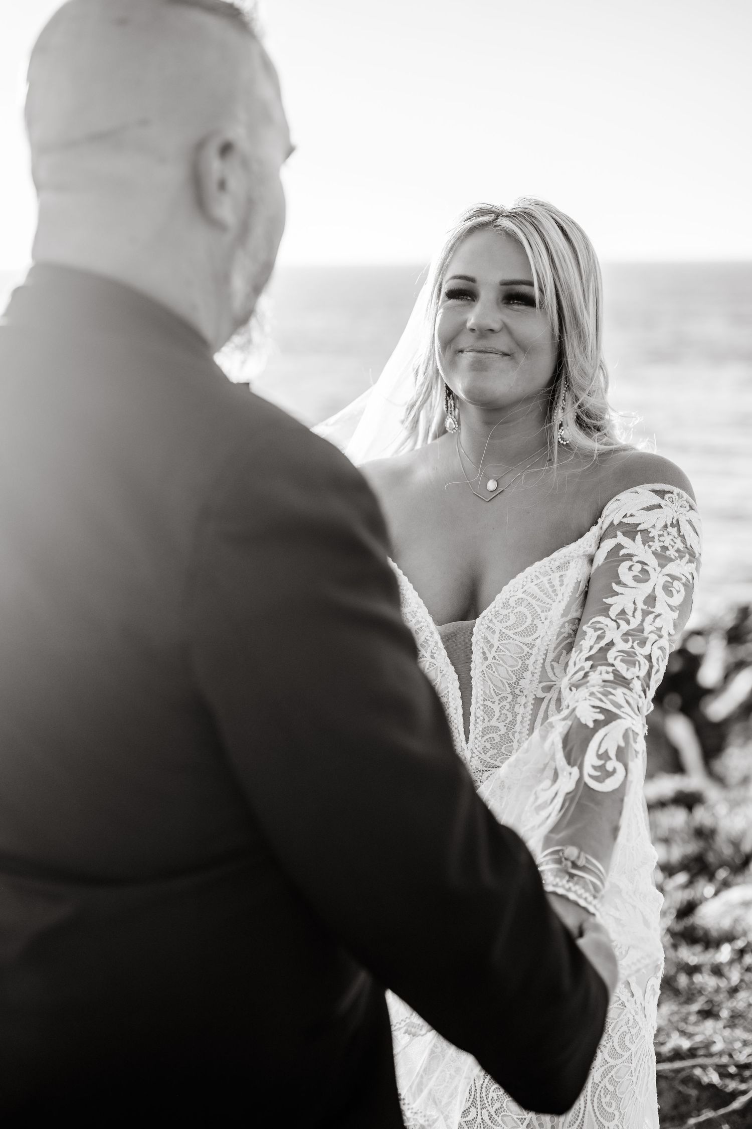 A romantic wedding ceremony moment captured in black and white with a lace dress detail.
