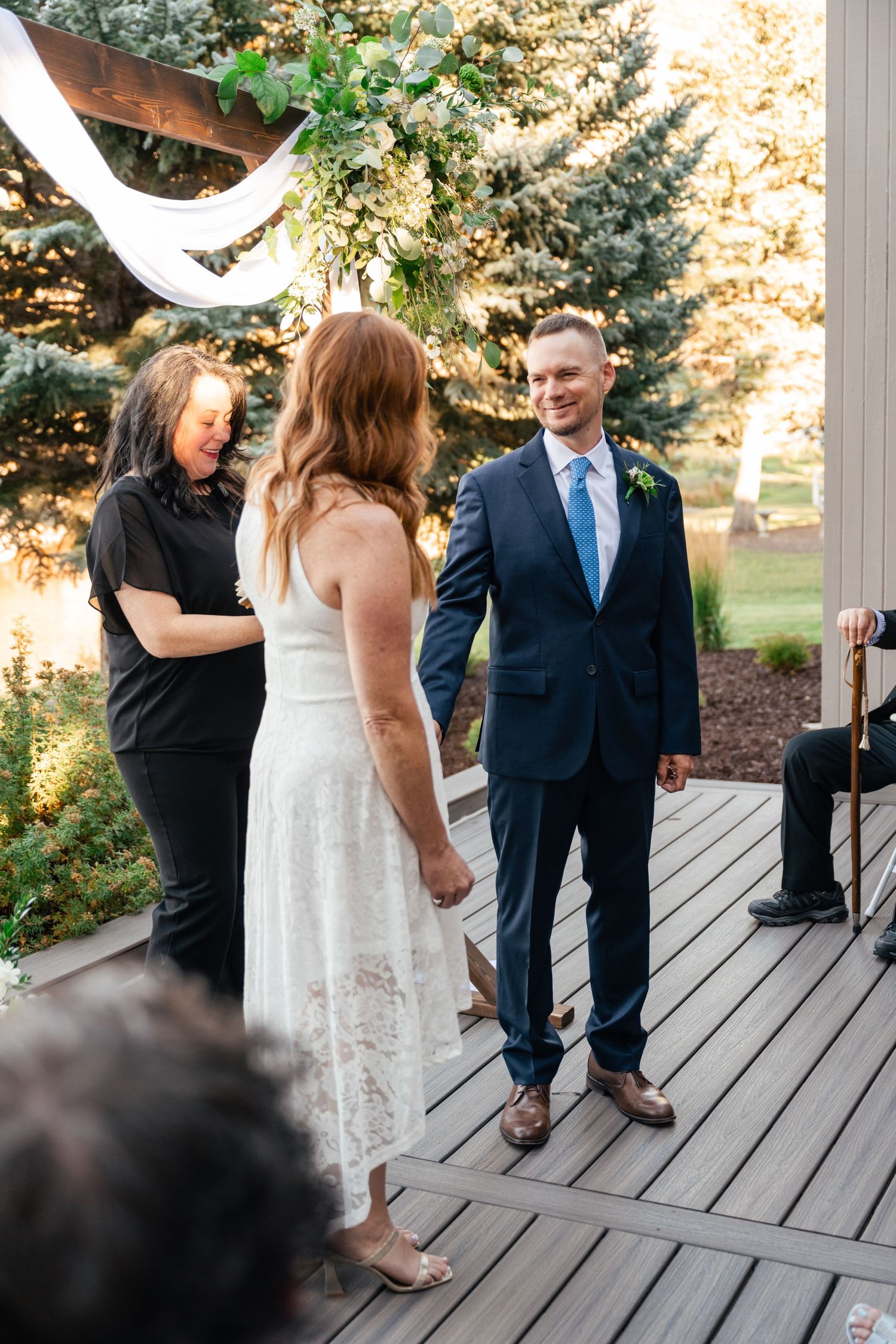 Wedding ceremony taking place on a wooden deck with guests watching.