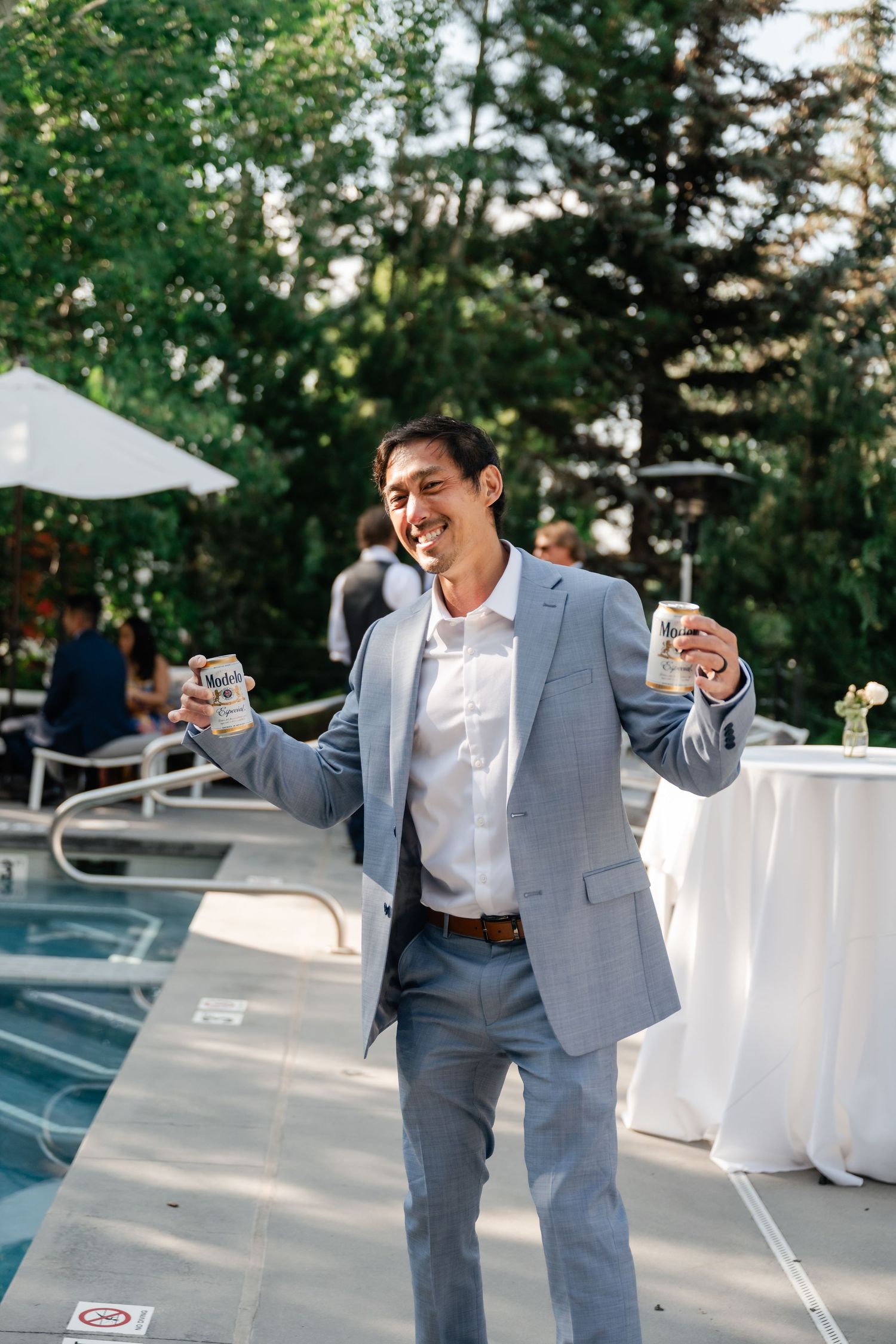 Wedding guest in grey suit dancing and celebrating outdoors at reception.