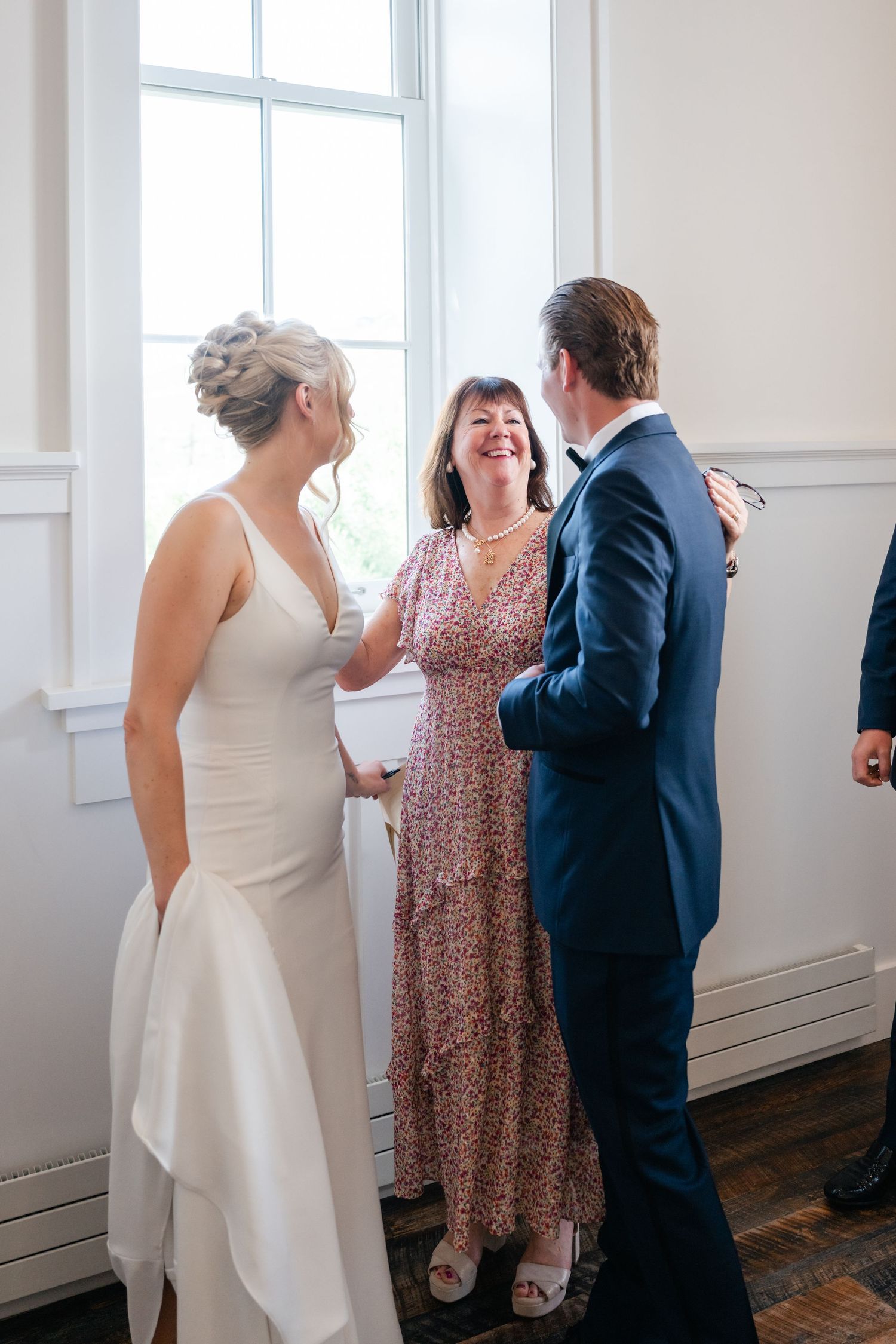 Three people engaged in cheerful conversation at an elegant indoor event.