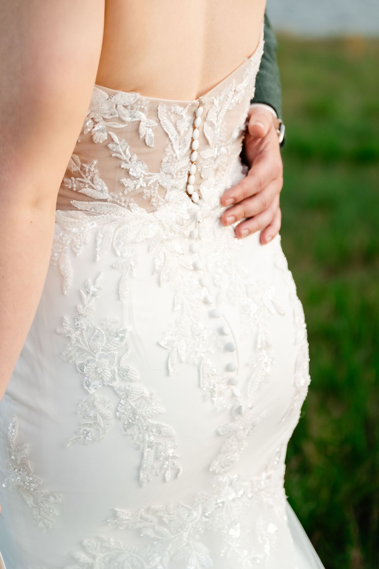 Close-up detail of intricate lace pattern on back of white wedding dress.