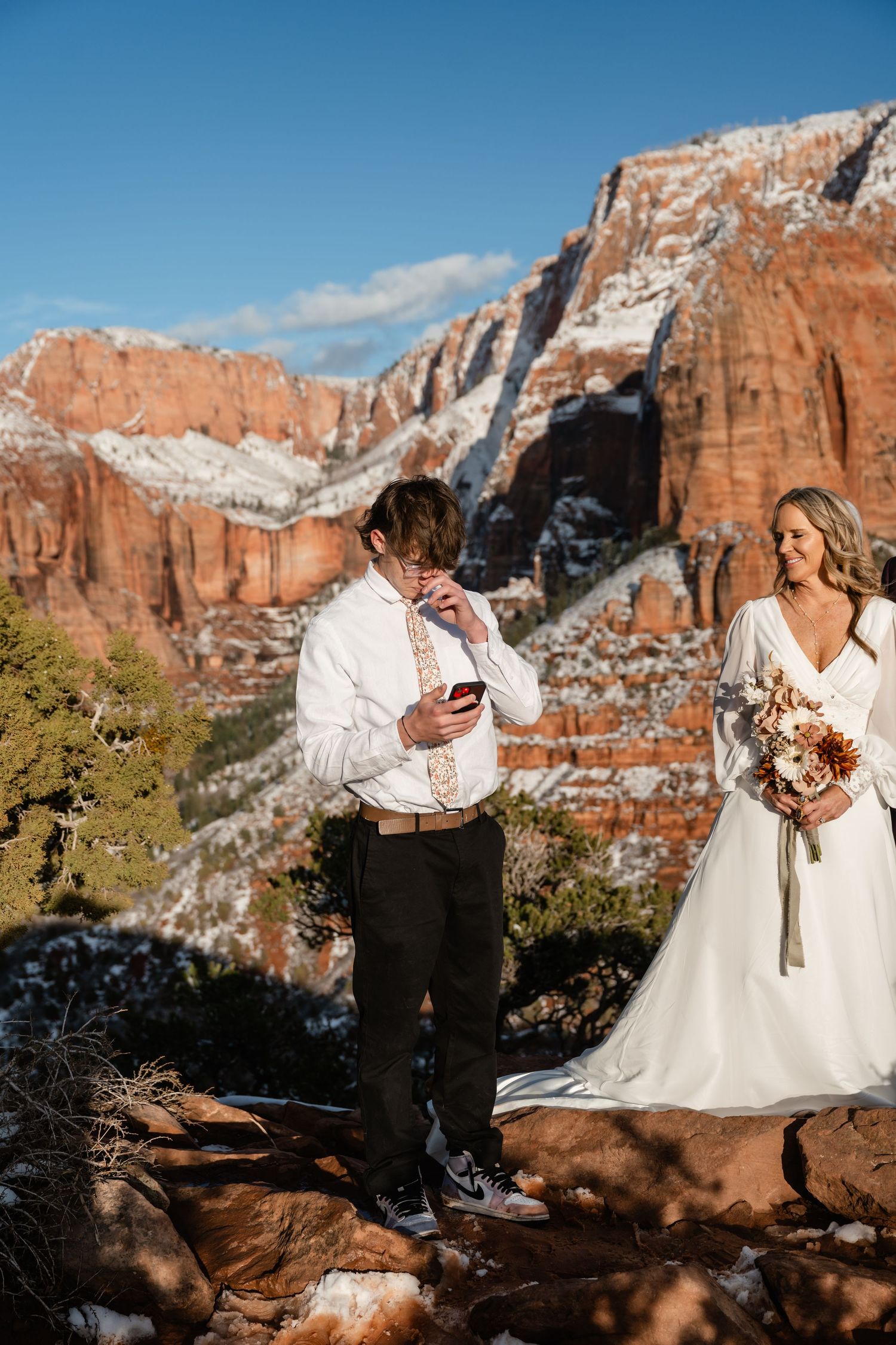 Wedding couple posing for photos with majestic red rock formations in Zion National Park.