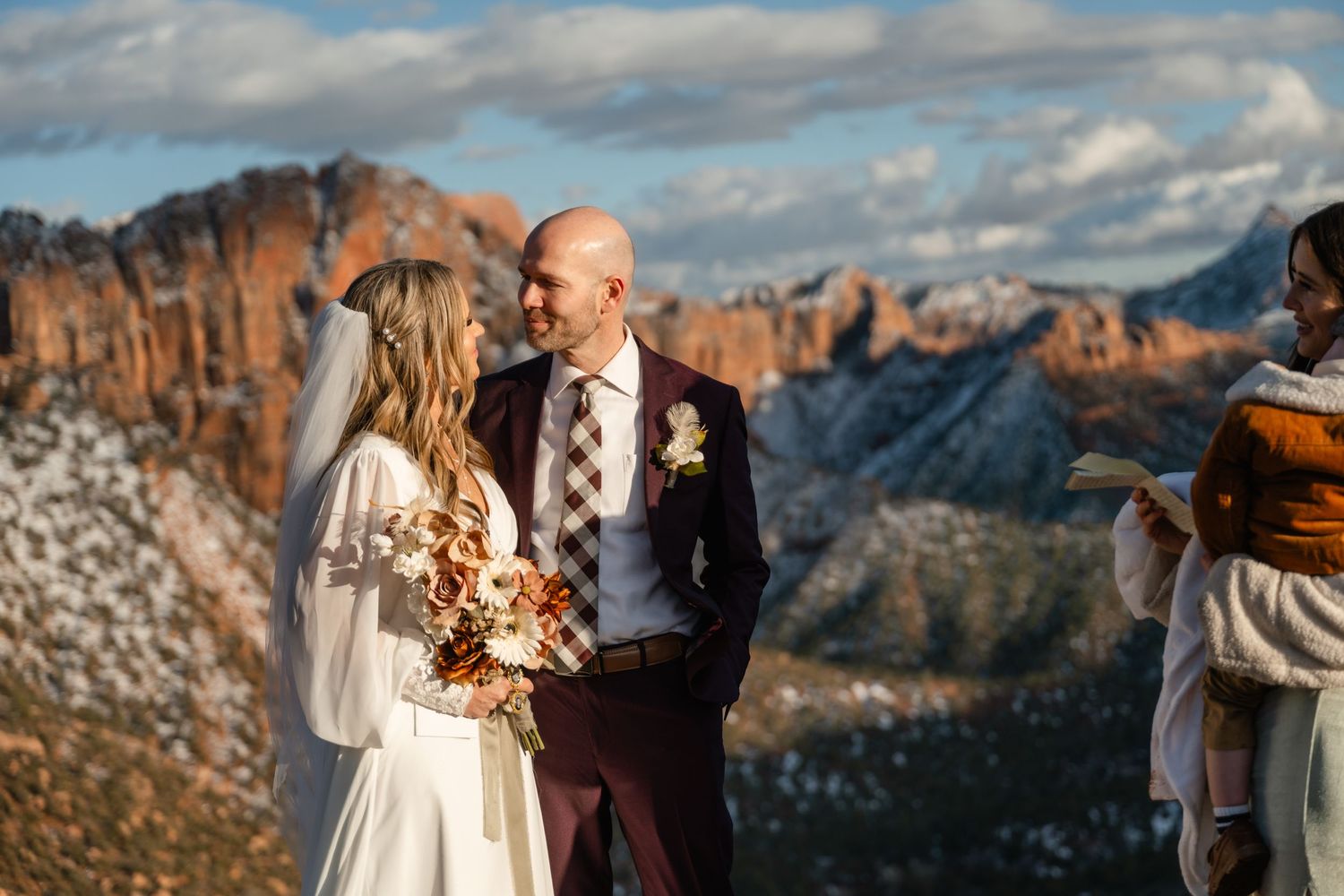Wedding ceremony with mountain landscape and red rock formations in background.