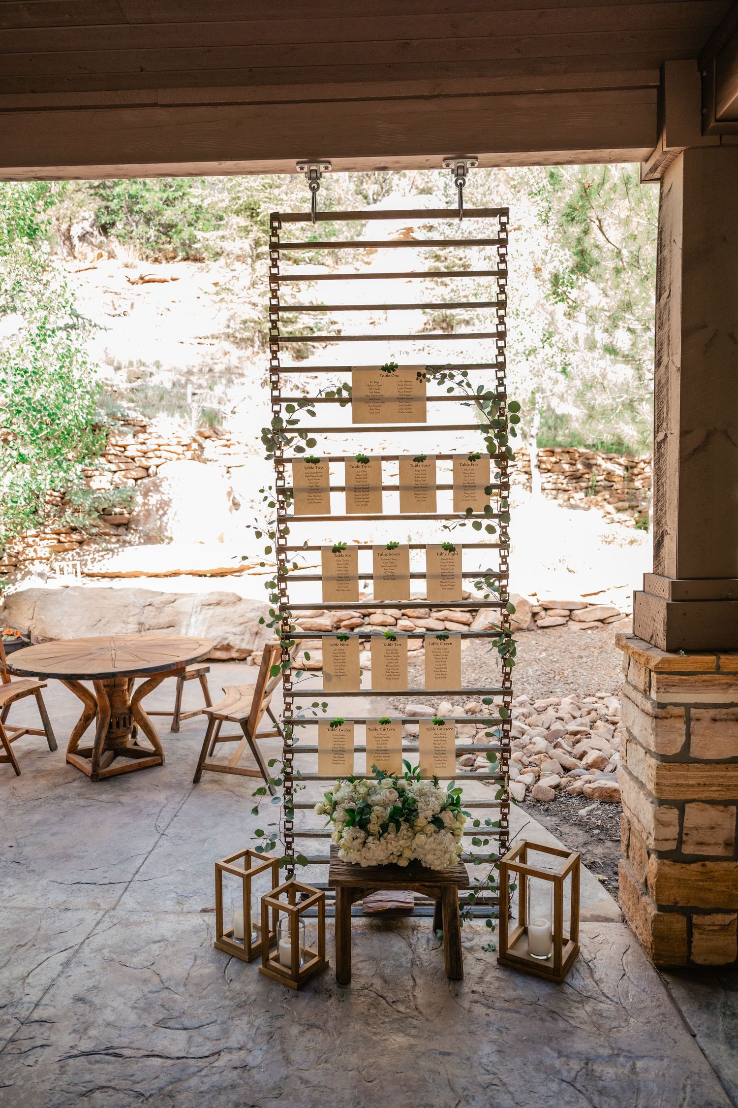 Rustic outdoor seating area with wooden chairs and string lights against a stone wall.