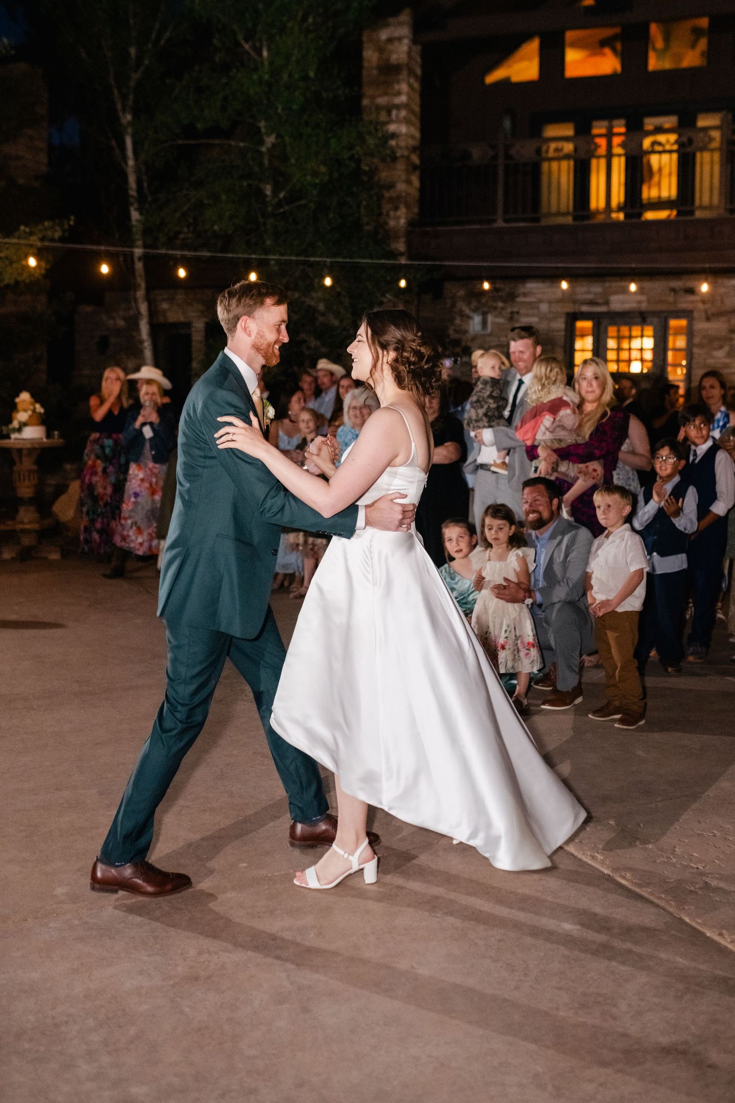 A couple dances together during their first dance at an outdoor wedding reception.