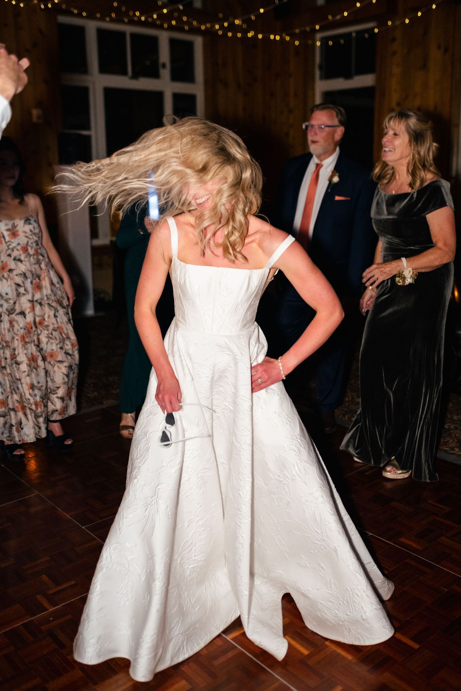 Wedding reception dance floor scene with twirling white dress under warm indoor lighting.