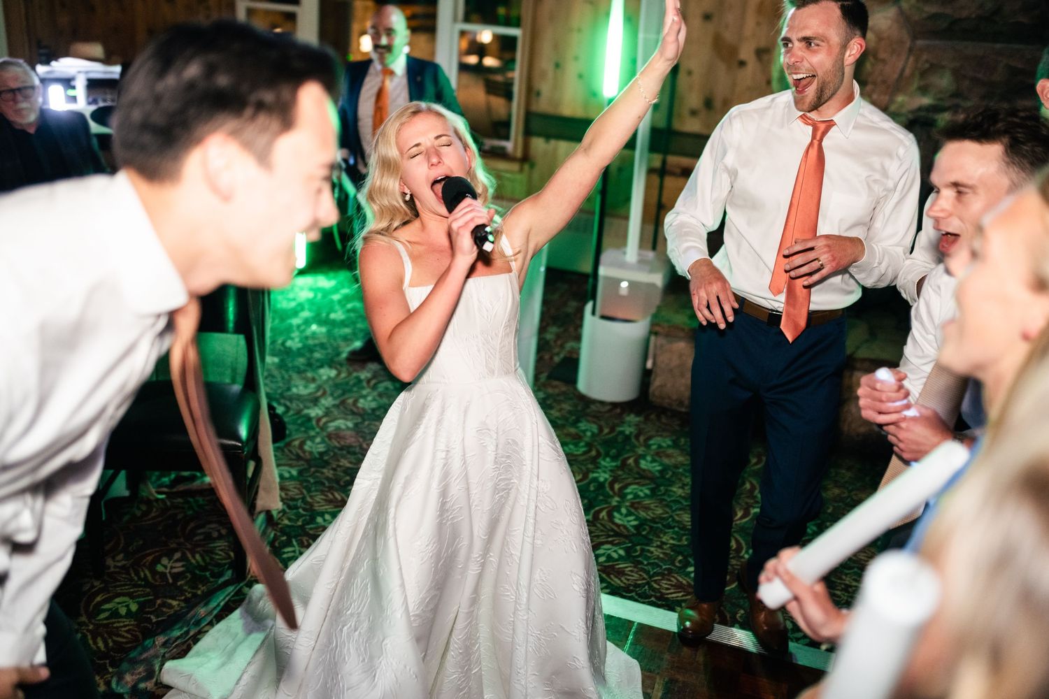 Wedding guests dancing and celebrating on wooden dance floor.